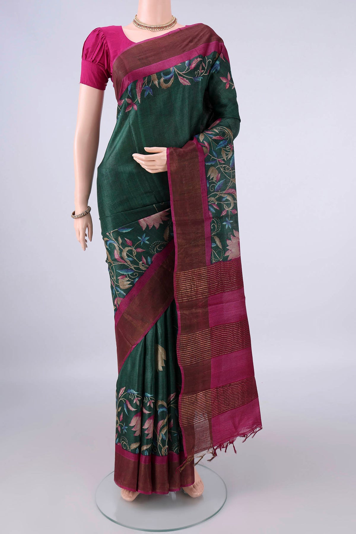 Bottle Green Tussar Saree with Printed design on the body and Zari Border.  displayed on a mannequin