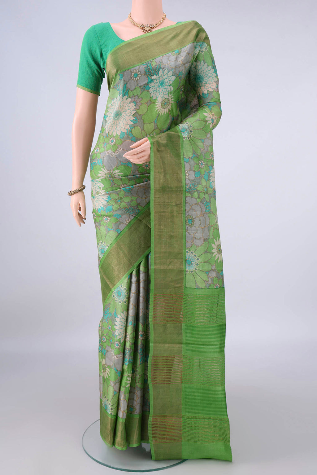 Green Tussar Saree with Floral Print on the body and Zari Border.  displayed on a mannequin