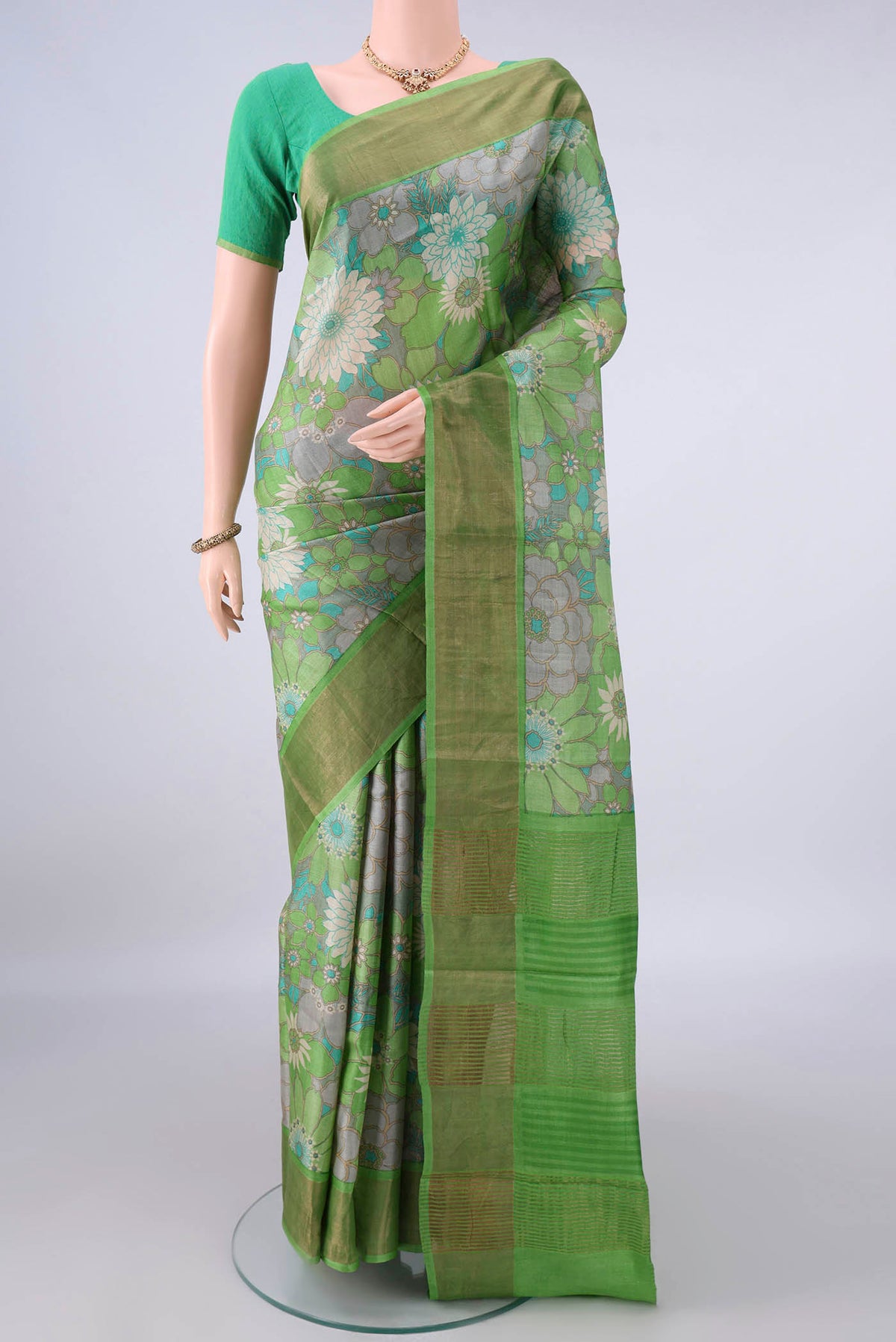 Green Tussar Saree with Floral Print on the body and Zari Border.  displayed on a mannequin