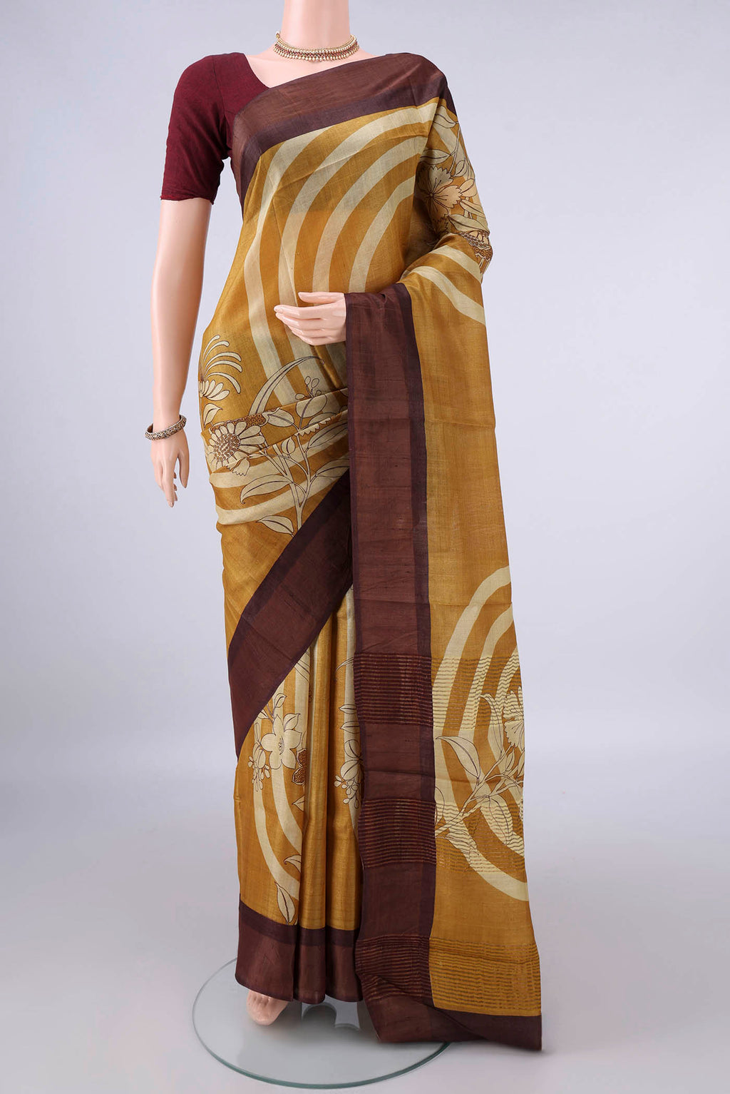 Mustard Tussar Saree with Printed design on the body and Zari Border.  displayed on a mannequin