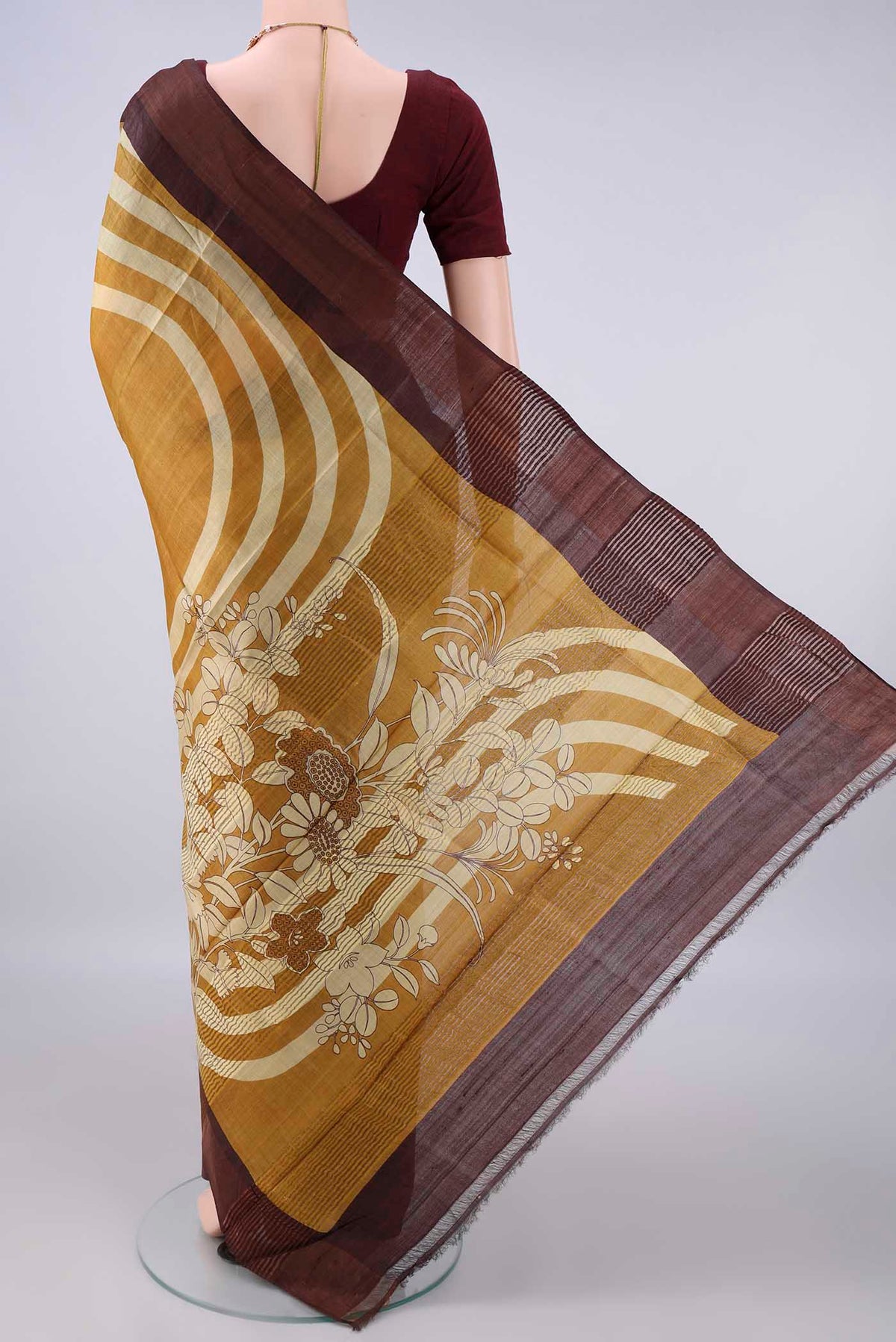 Flat view of Mustard Tussar Saree with Printed design on the body and Zari Border. 
