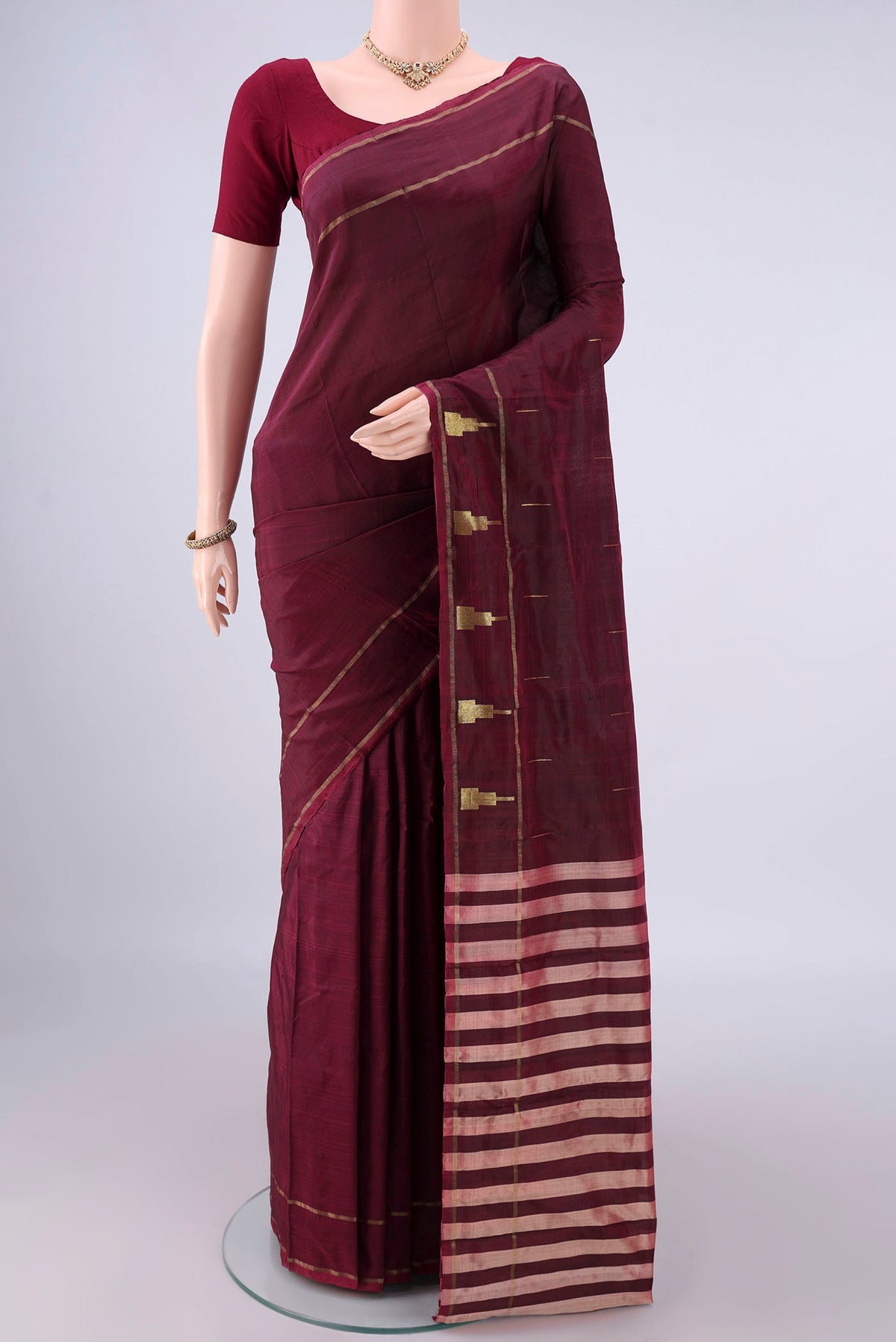Pure Silk Maroon Kanchipuram Saree with Zari Butta on the body and Zari Border.  displayed on a mannequin