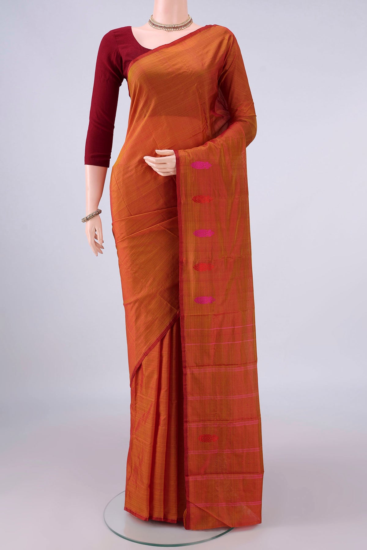Pure Silk Rust Kanchipuram Saree with Plain Body and Thread Border.  displayed on a mannequin