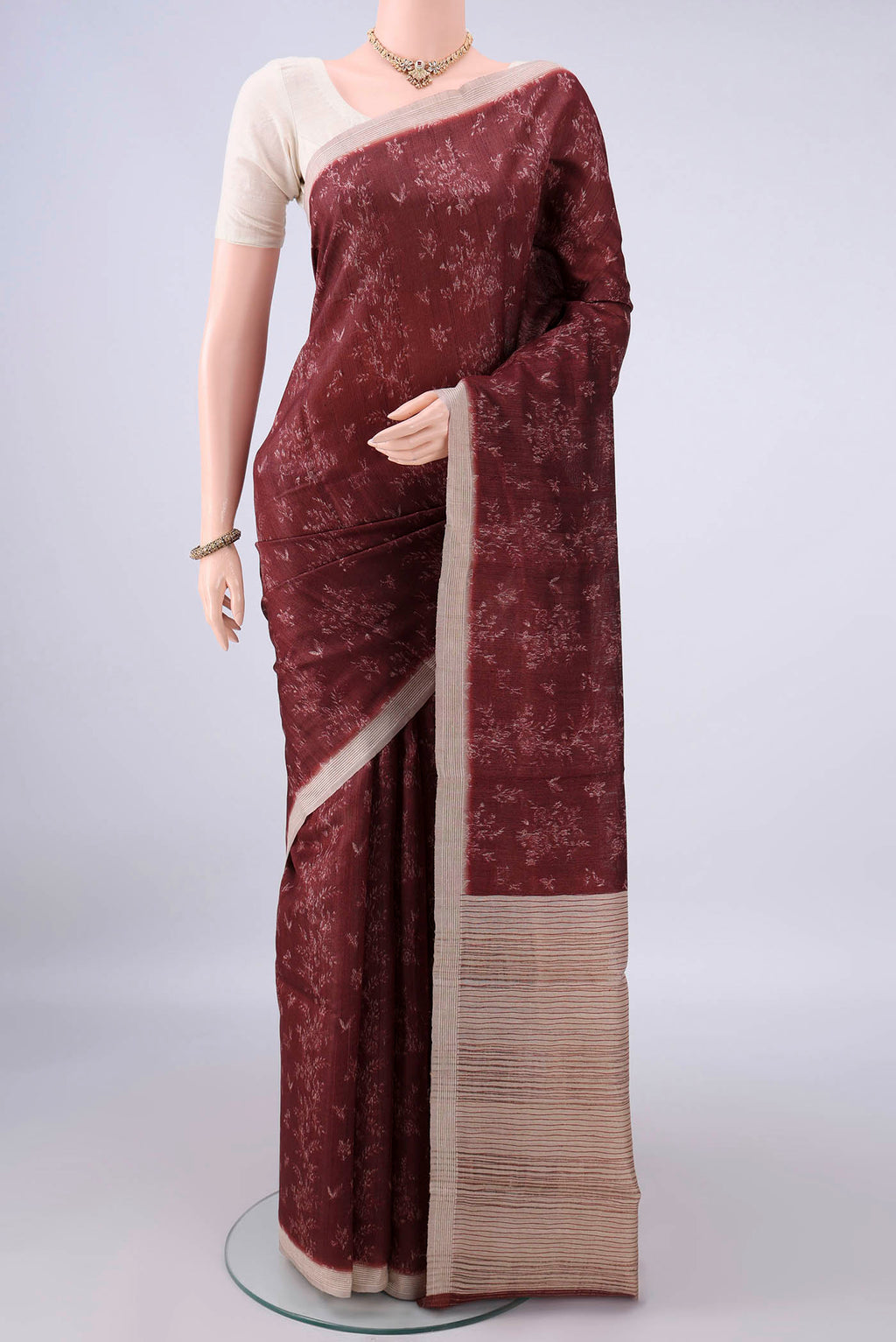 Brown Tussar Saree with Printed design on the body and Zari Border.  displayed on a mannequin