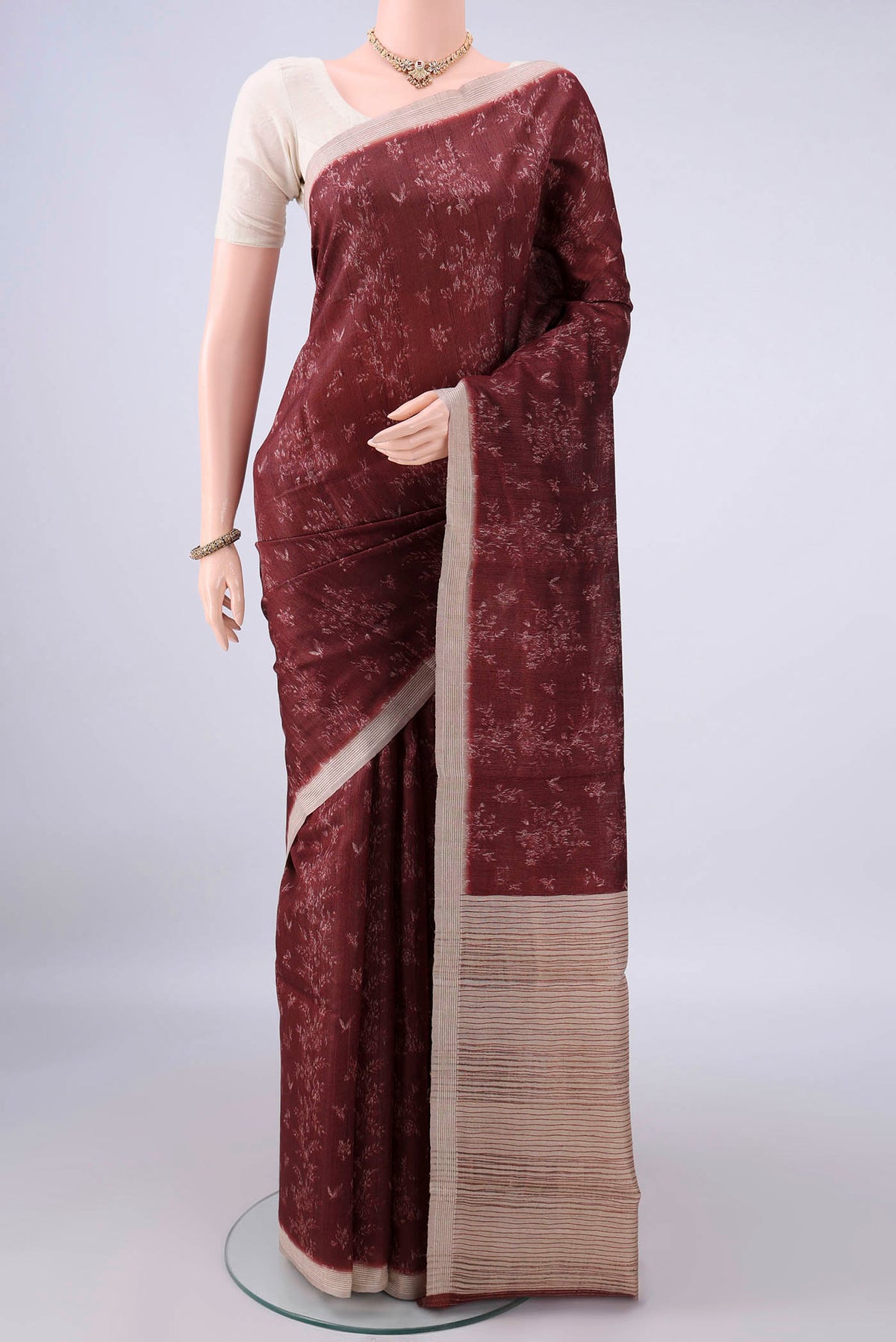 Brown Tussar Saree with Printed design on the body and Zari Border.  displayed on a mannequin