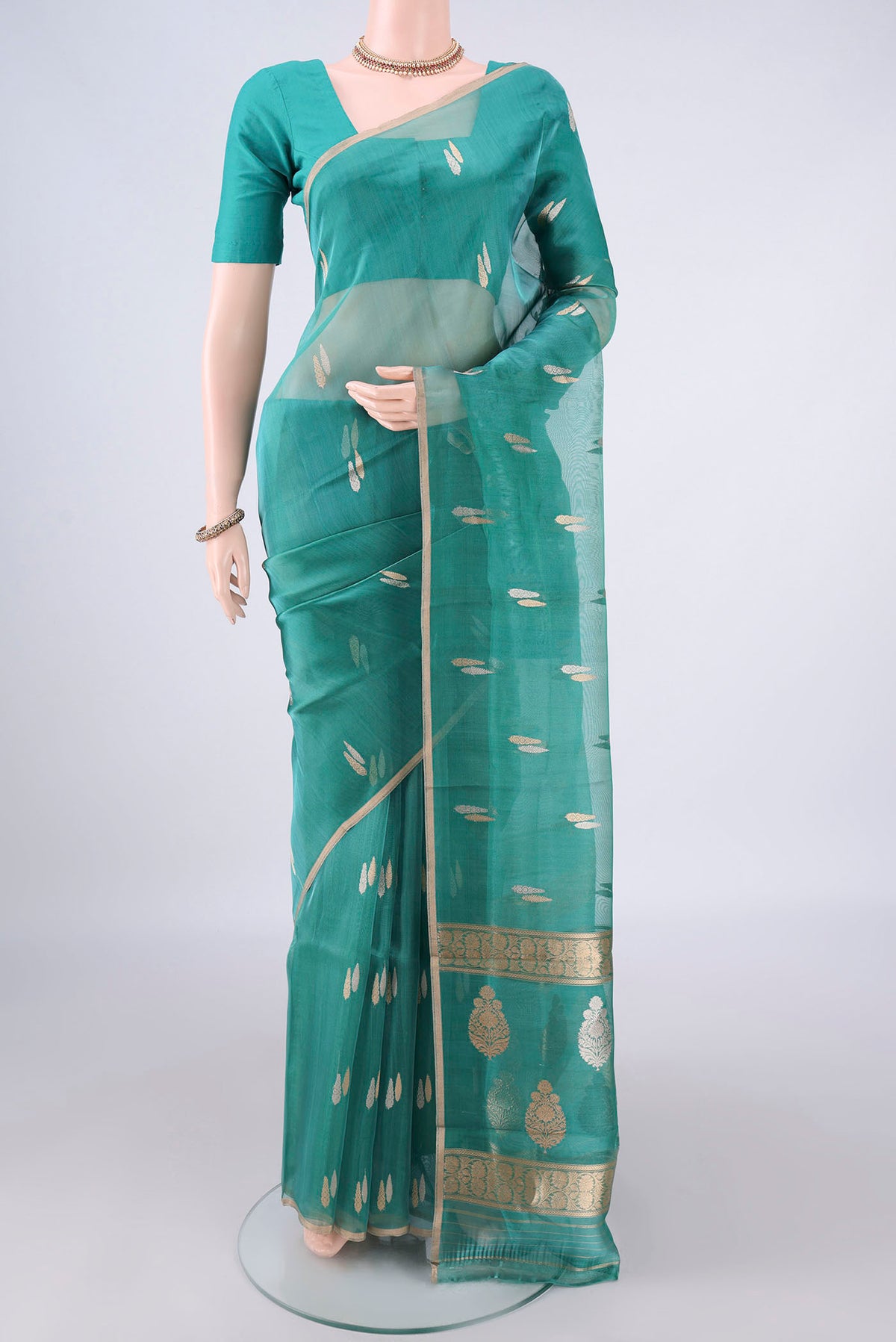 Sea Green Organza Saree with Zari Butta on the body and Thin Zari Line.  displayed on a mannequin