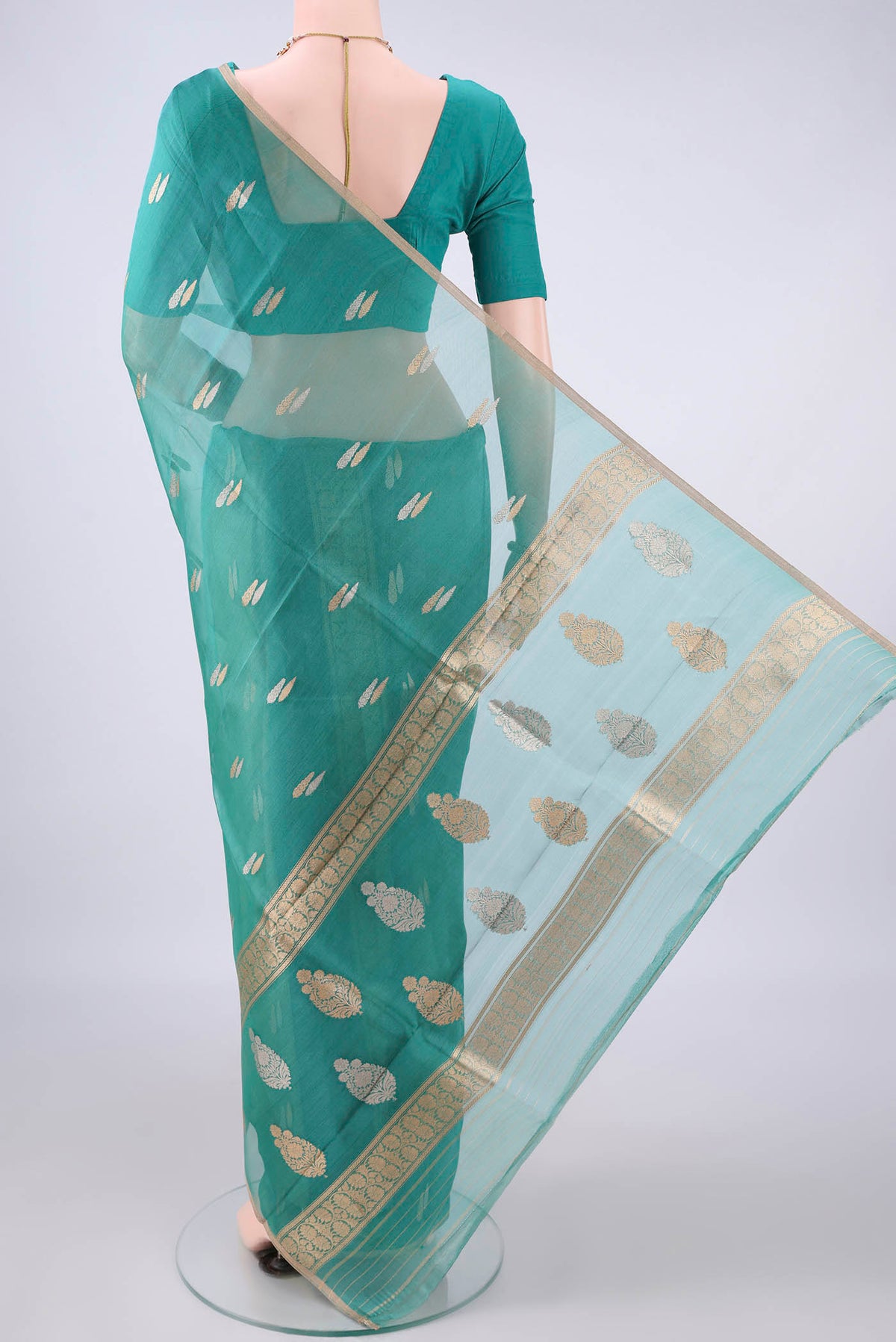 Flat view of Sea Green Organza Saree with Zari Butta on the body and Thin Zari Line. 