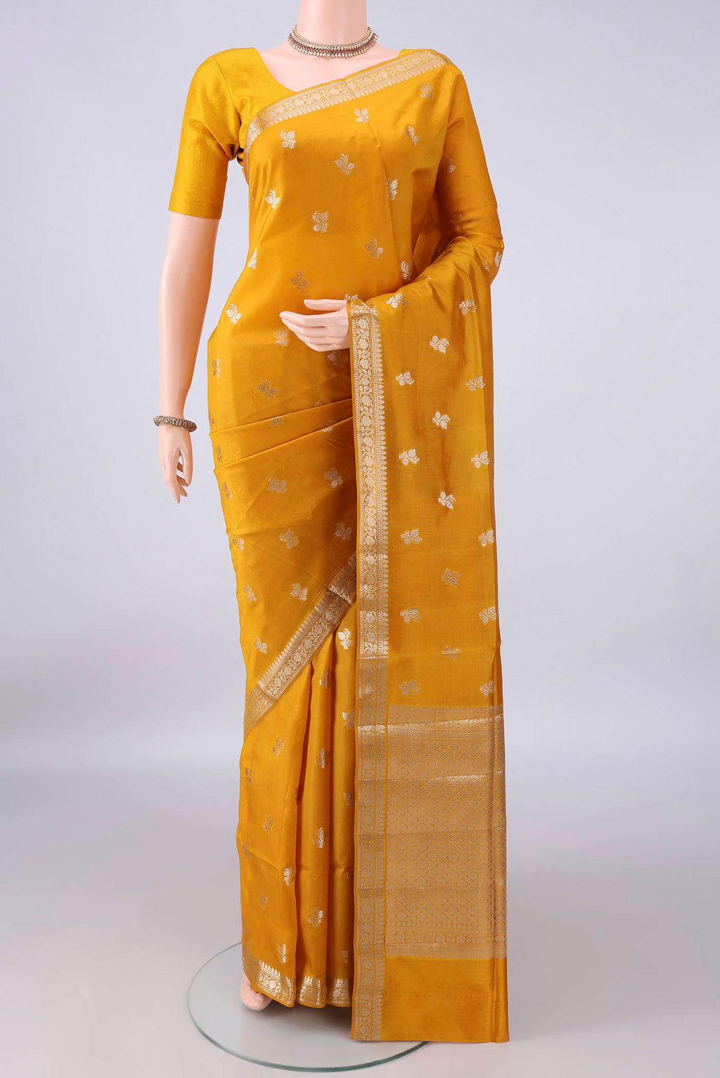 Pure Silk Mustard Banarasi Raw Saree with Zari Butta on the body and Zari Border.  displayed on a mannequin