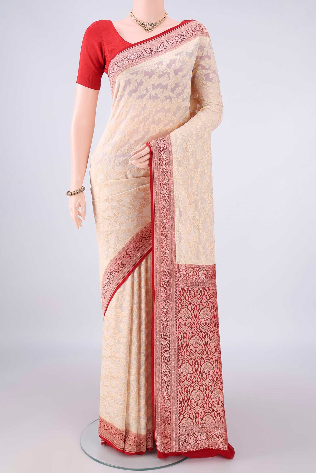 Cream Banarasi Georgette Saree with Zari Butta on the body and Zari Border.  displayed on a mannequin