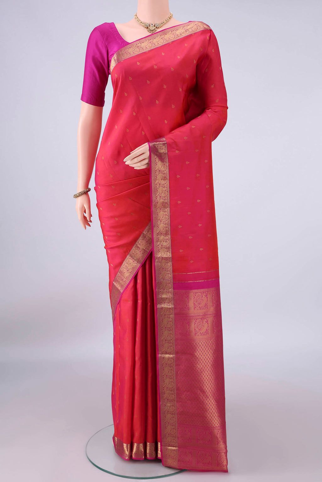 Pure Silk Coral Kanchipuram Saree with Zari Butta on the body and Zari Border.  displayed on a mannequin