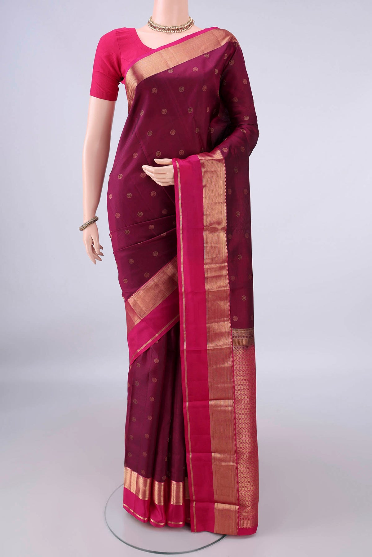 Pure Silk Burgundy Kanchipuram Saree with Zari Butta on the body and Zari Border.  displayed on a mannequin