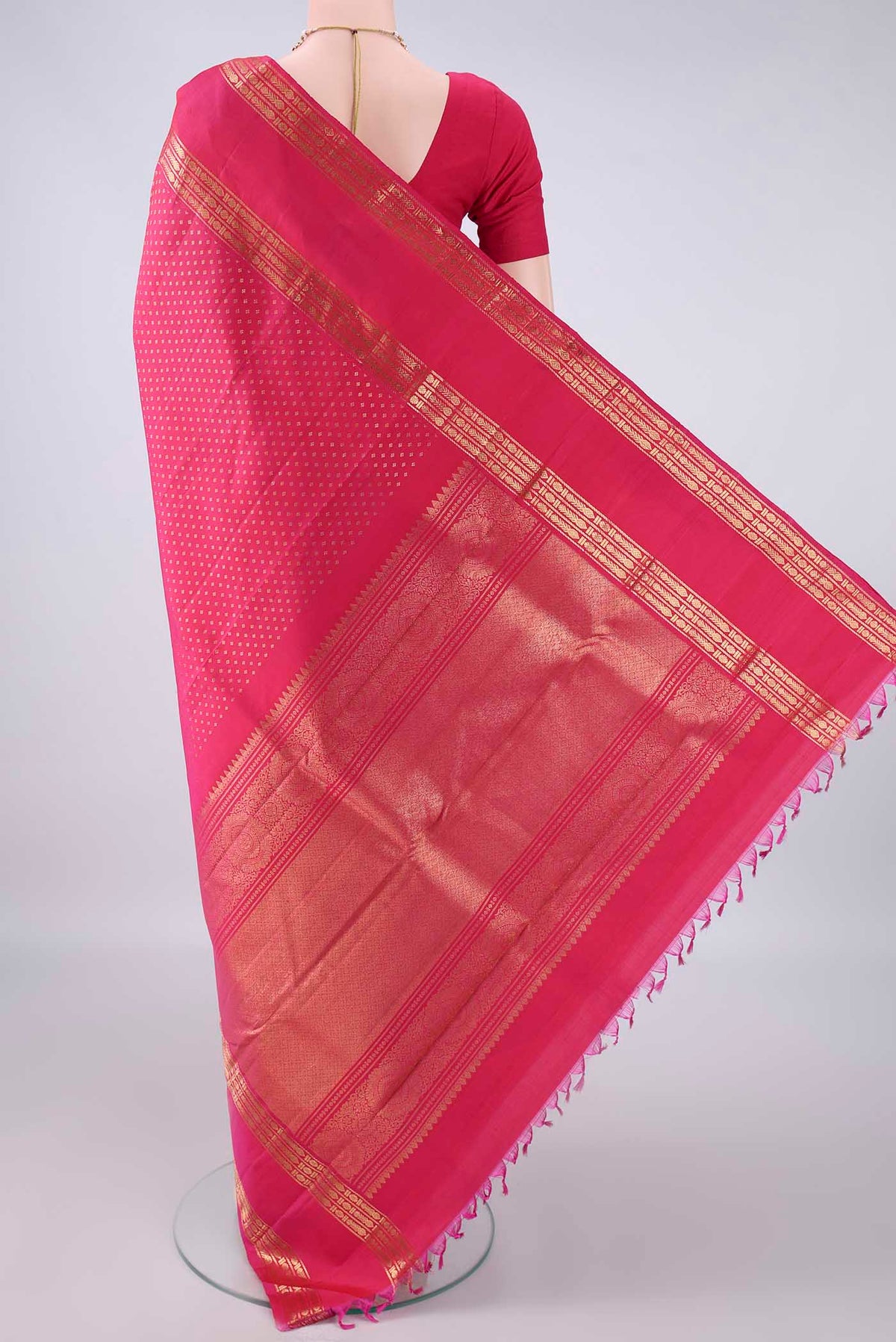 Flat view of Pure Silk Rani Pink Kanjivaram Saree with Zari Butta on the body and Zari Border. 