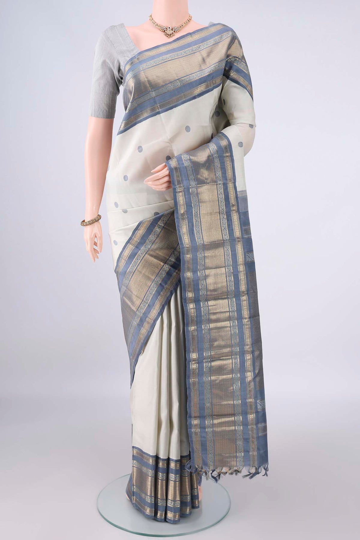 Pure Silk Off White Kanchipuram Saree with Thread Butta on the body and Zari Border.  displayed on a mannequin