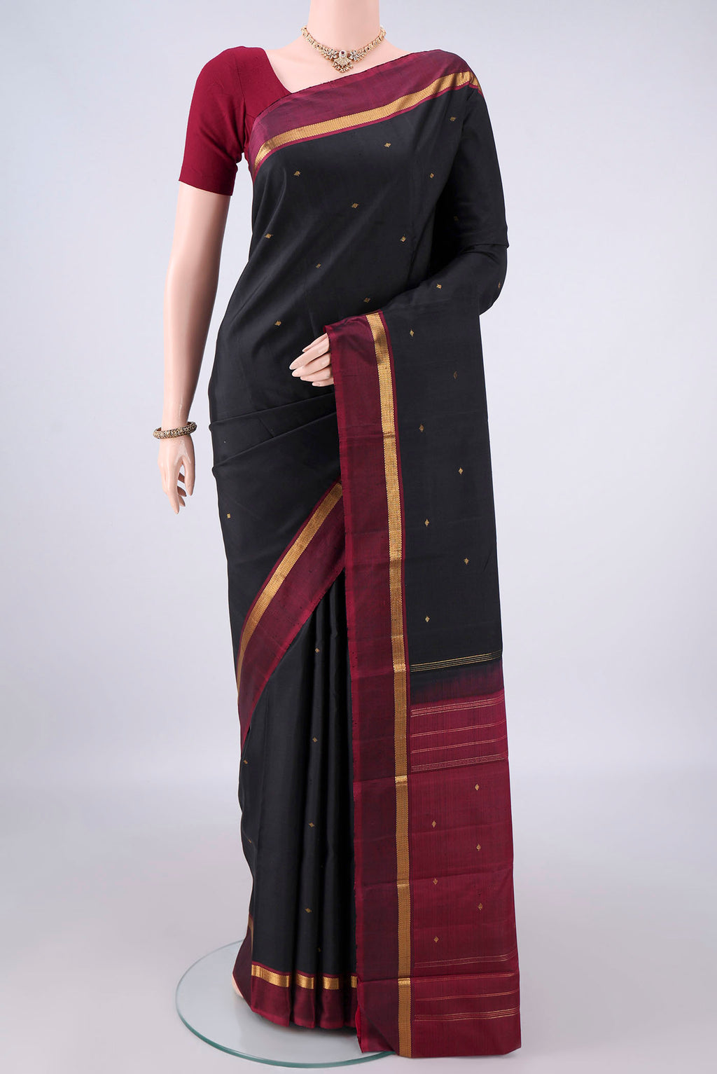 Pure Silk Black Kanjivaram Saree with Zari Butta on the body and Zari Border.  displayed on a mannequin