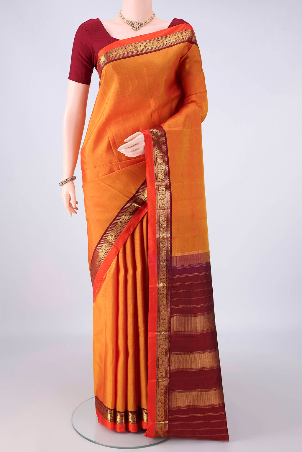 Pure Silk Orange Kanchipuram Saree with Plain Body and Zari Border.  displayed on a mannequin