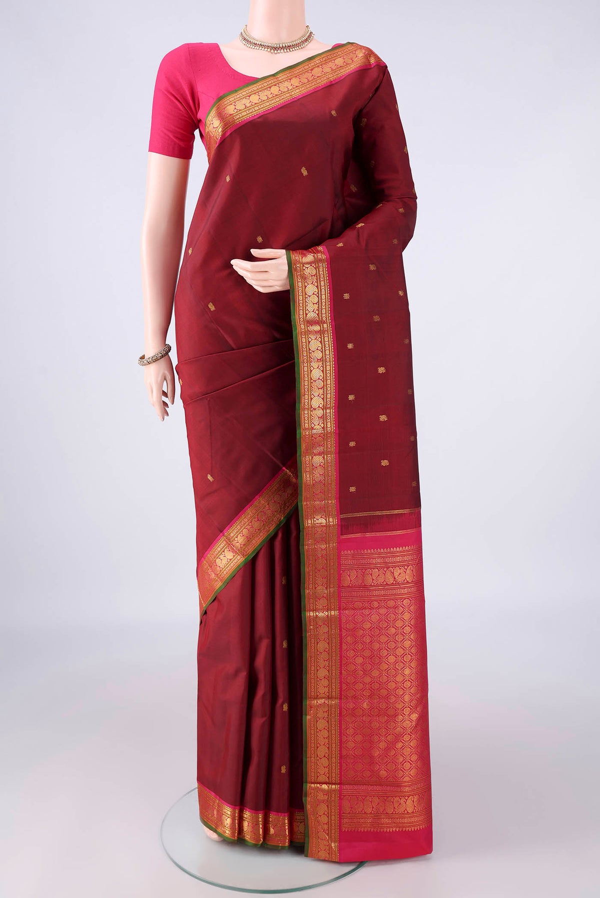 Pure Silk Maroon Kanjivaram Saree with Zari Butta on the body and Zari Border.  displayed on a mannequin