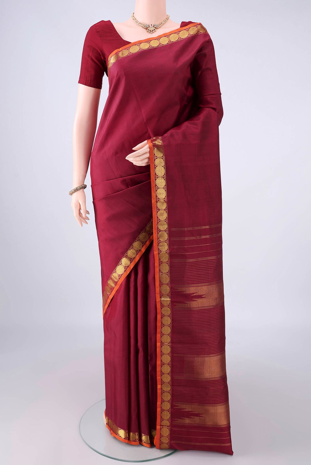 Pure Silk Maroon Kanjivaram Saree with Plain Body and Zari Border.  displayed on a mannequin