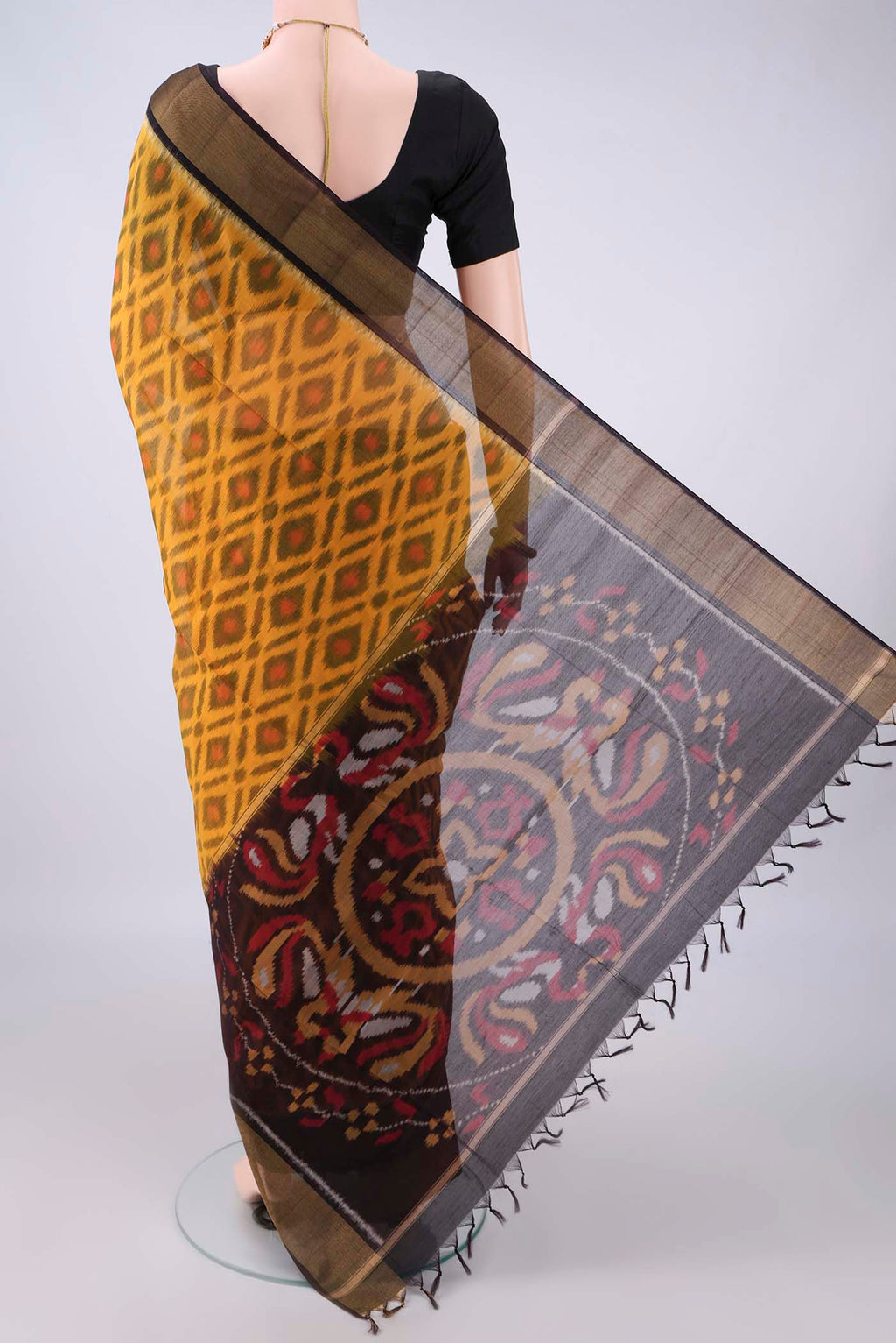 Flat view of Yellow Silk Cotton Saree with Ikat design on the body and Zari Border. 