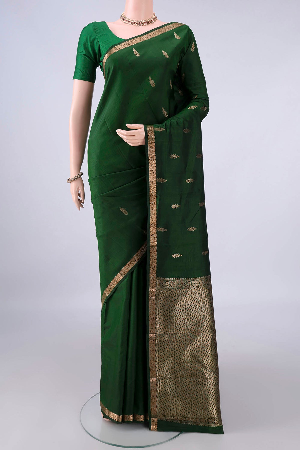 Pure Silk Bottle Green Kanjivaram Saree with Zari Butta on the body and Zari Border.  displayed on a mannequin