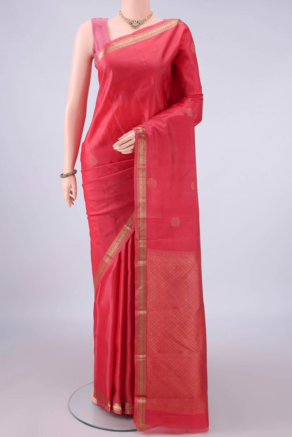 Pure Silk Coral Kanjivaram Saree with Zari Butta on the body and Zari Border.  displayed on a mannequin