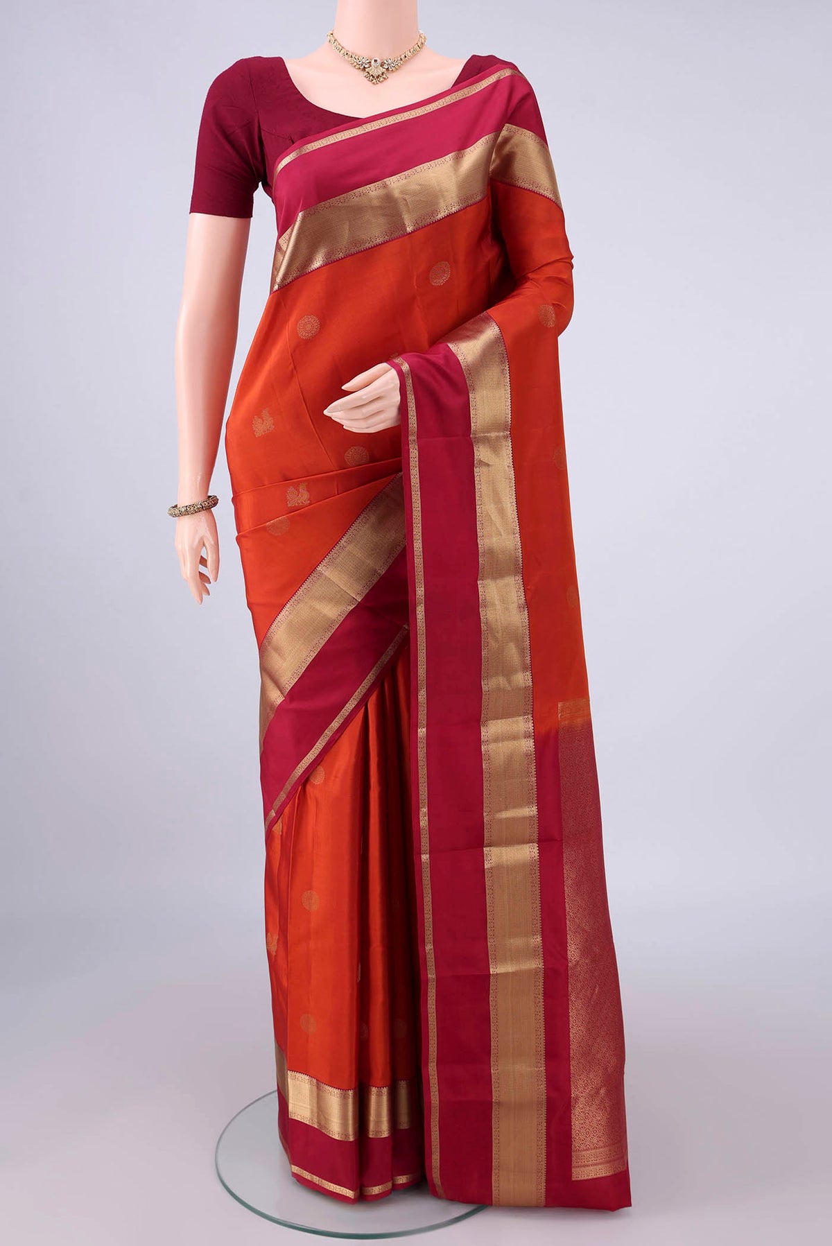 Pure Silk Orange Kanchipuram Saree with Zari Butta on the body and Zari Border.  displayed on a mannequin