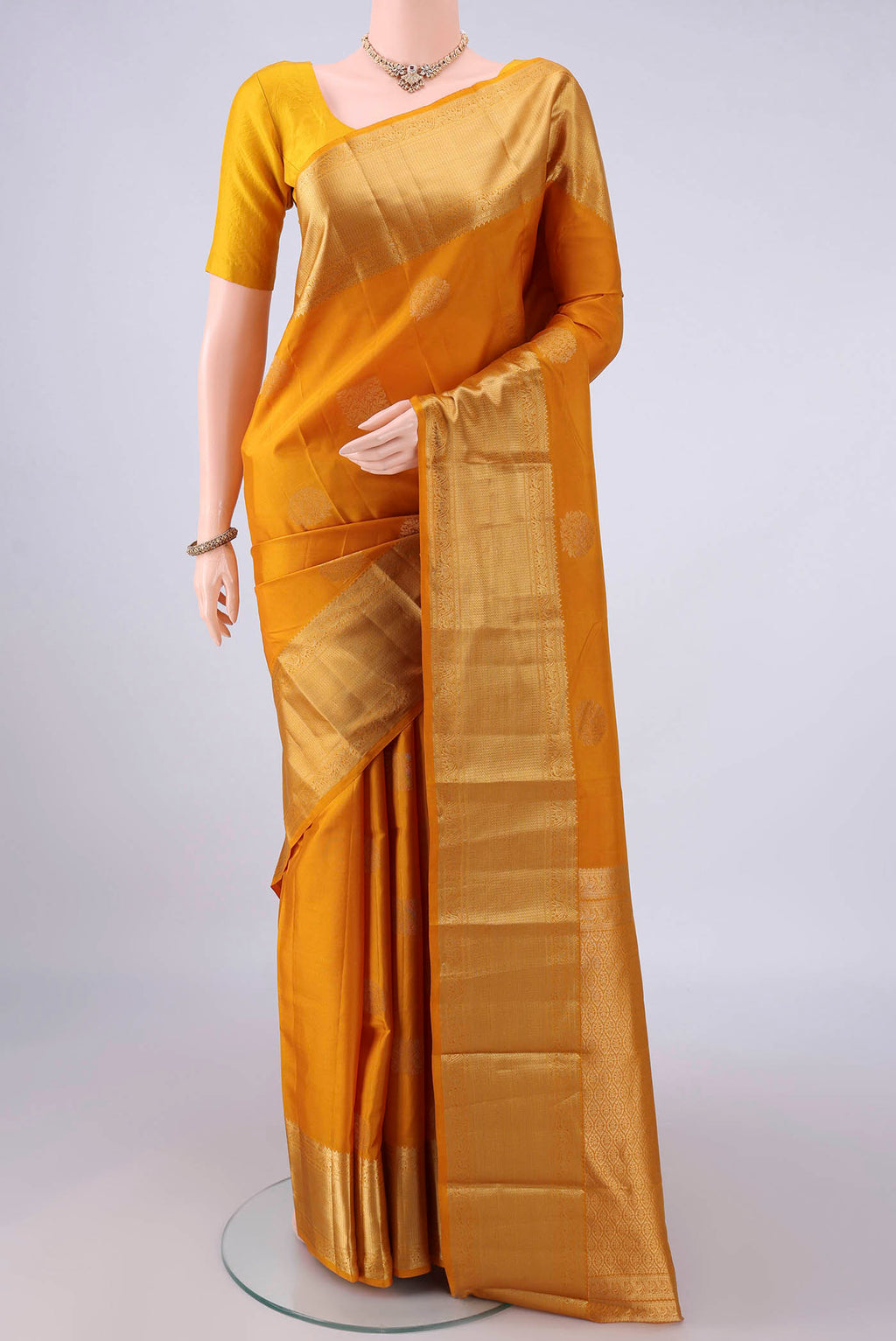 Pure Silk Mustard Kanchipuram Saree with Zari Butta on the body and Zari Border.  displayed on a mannequin