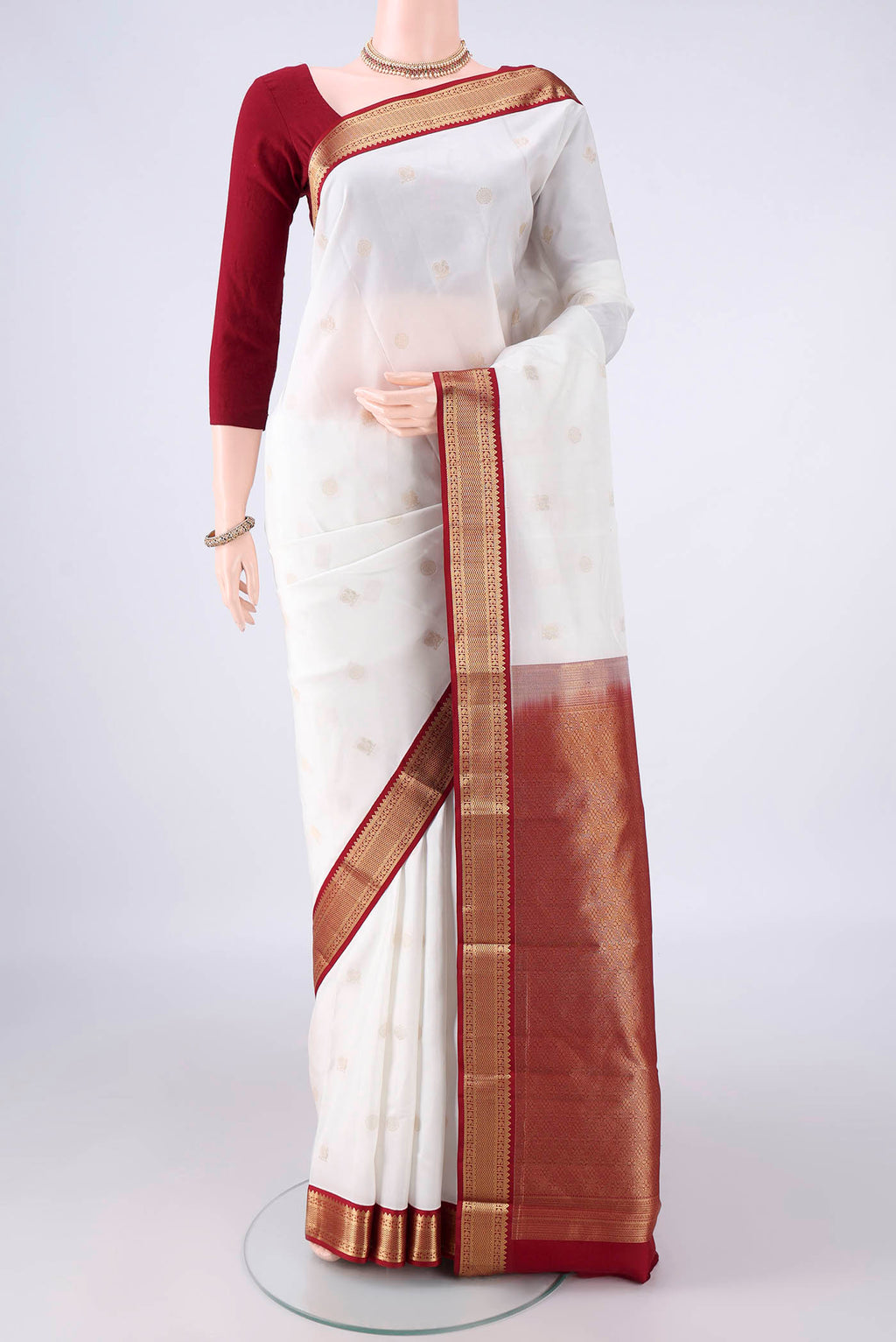 Pure Silk White Kanchipuram Saree with Zari Butta on the body and Zari Border.  displayed on a mannequin