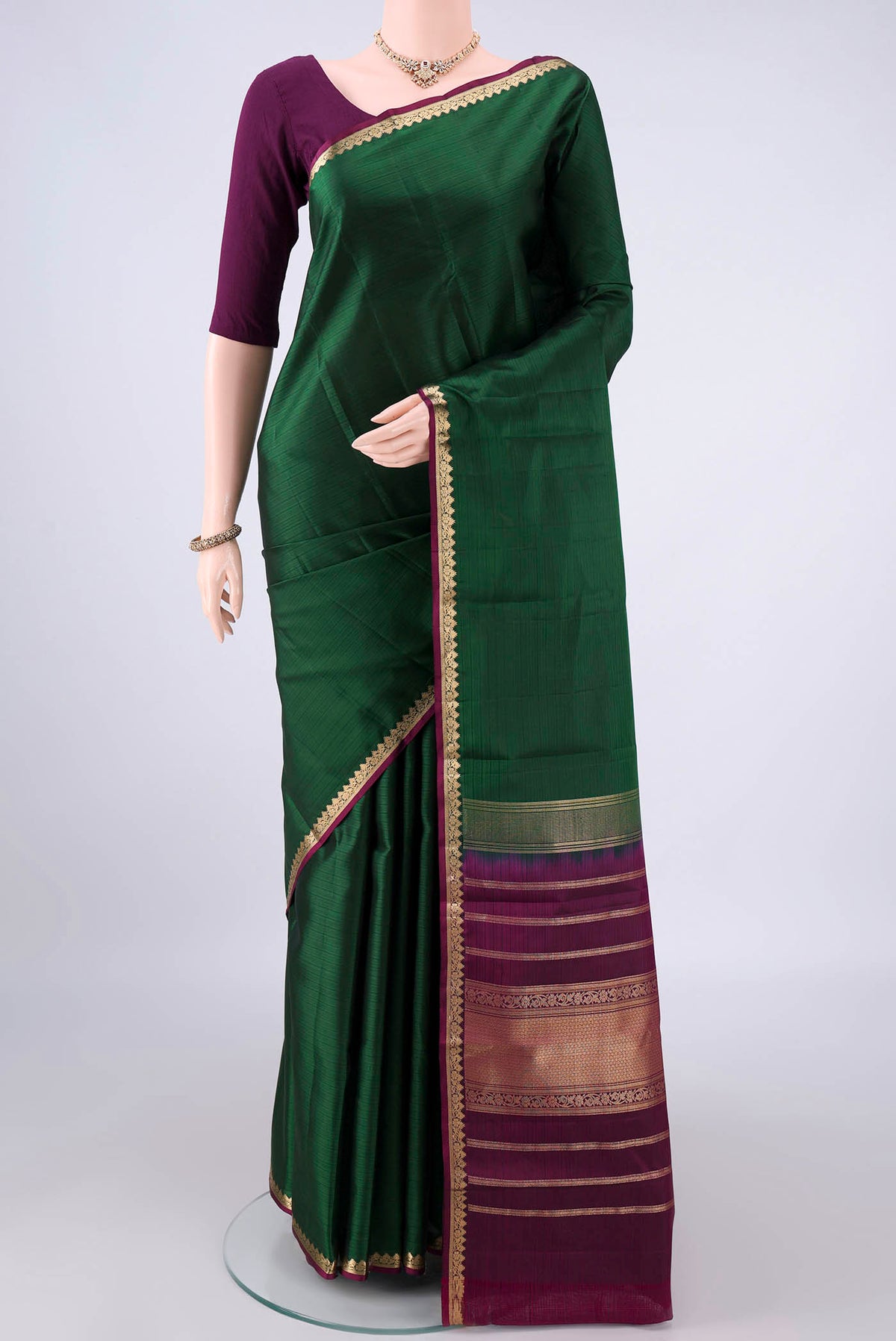 Pure Silk Bottle Green Kanjivaram Saree with Plain Body and Zari Border.  displayed on a mannequin