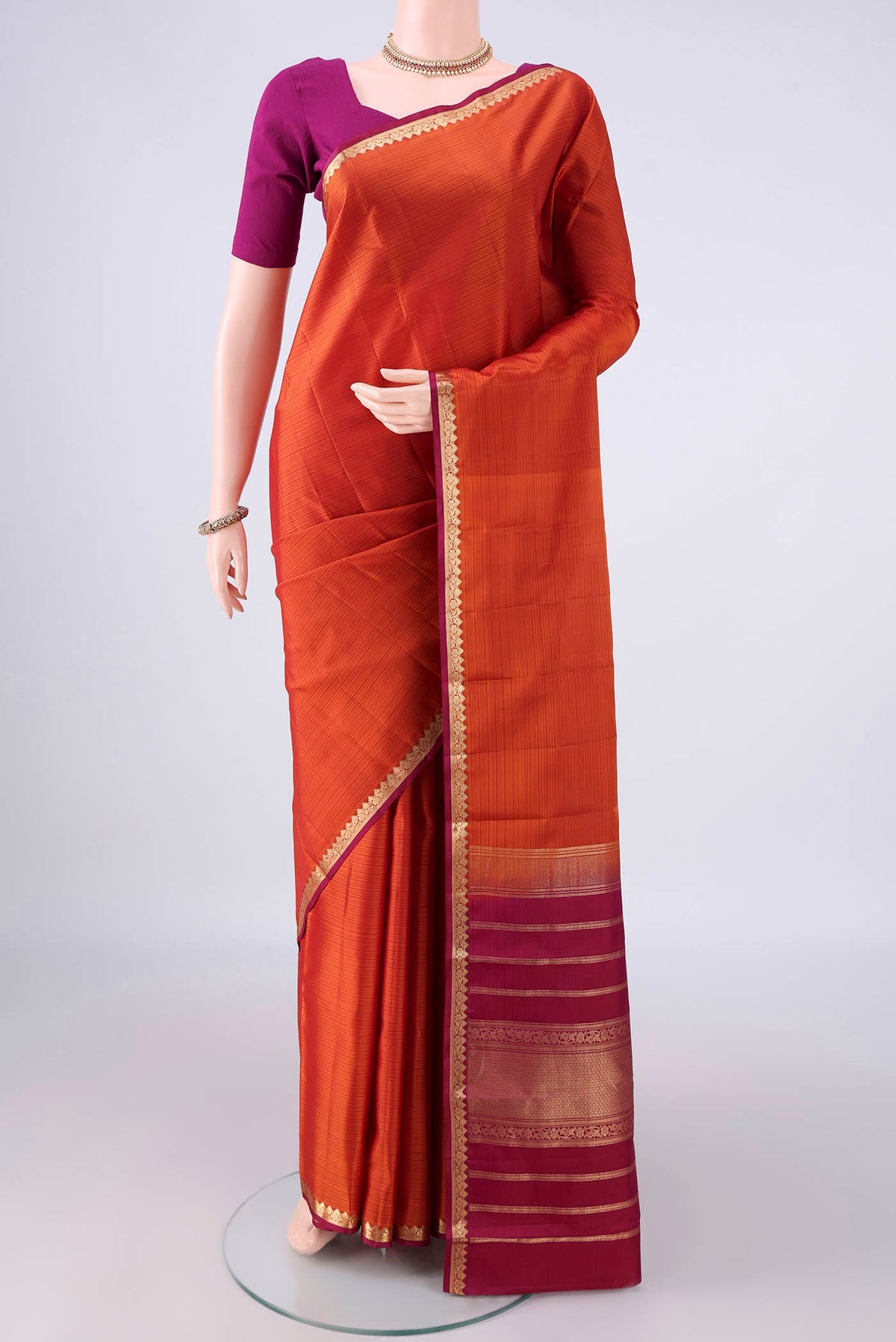 Pure Silk Orange Kanjivaram Saree with Plain Body and Zari Border.  displayed on a mannequin