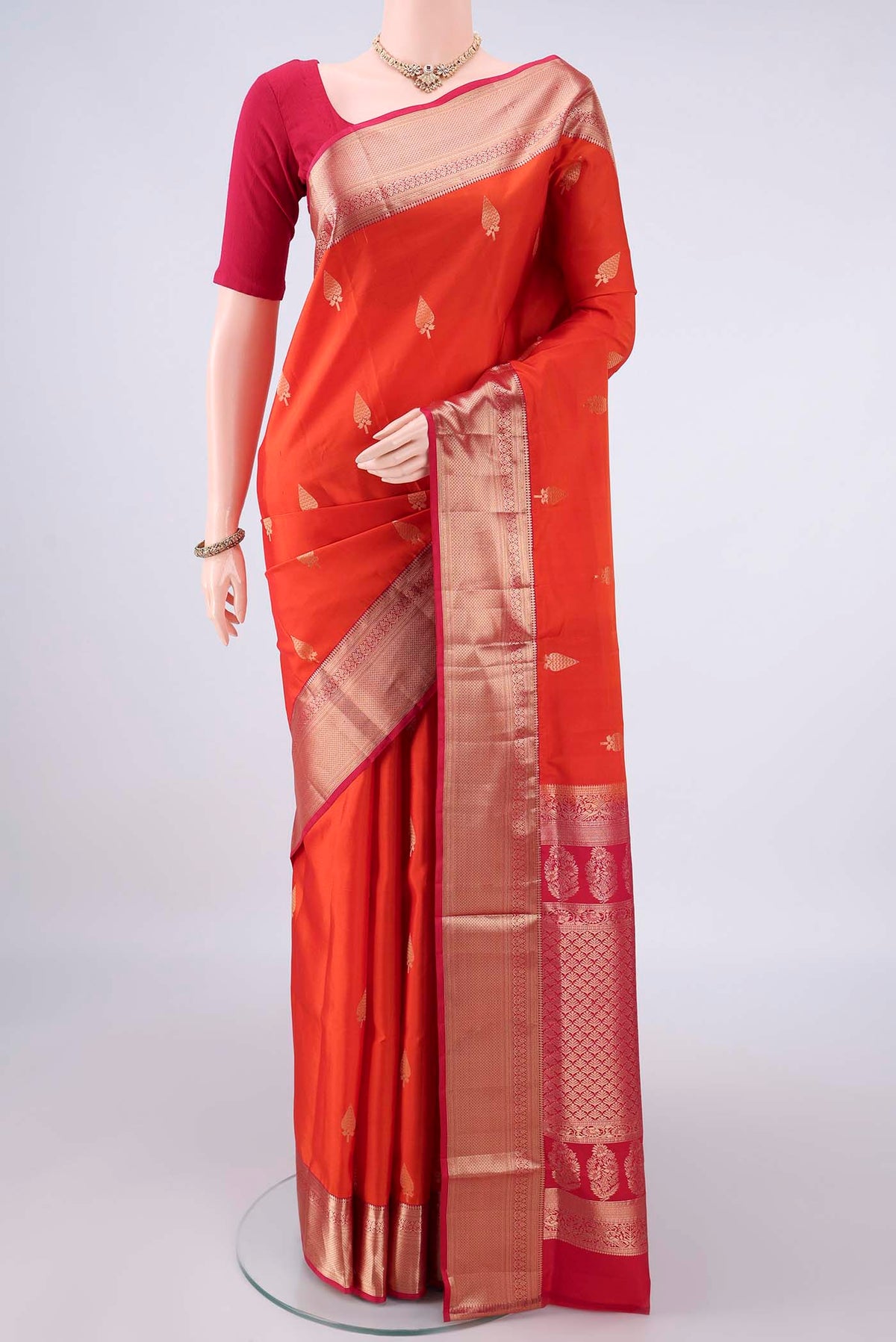 Pure Silk Orange Soft Saree with Zari Butta on the body and Zari Border.  displayed on a mannequin