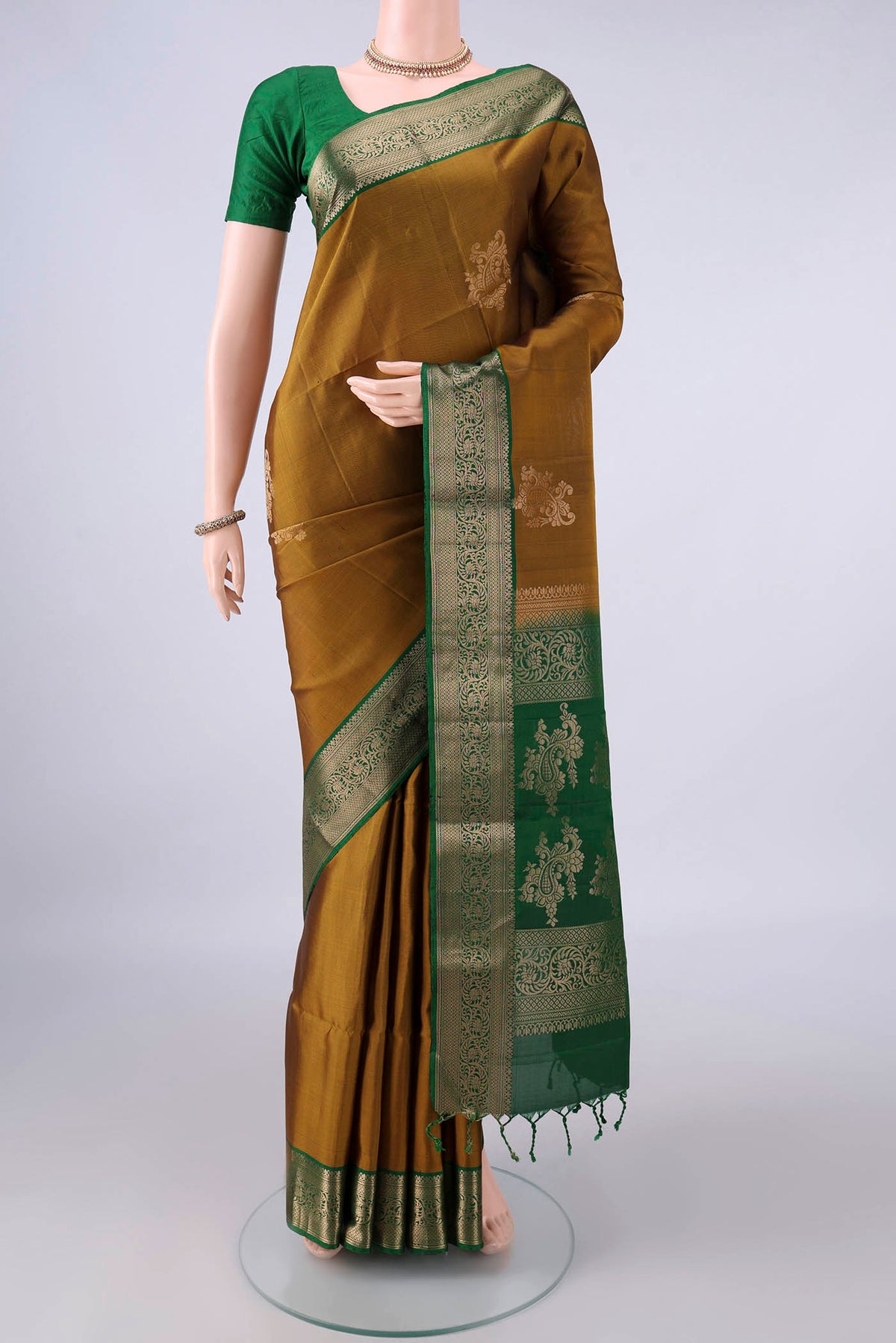 Pure Silk Mehandi Green Soft Saree with Zari Butta on the body and Zari Border.  displayed on a mannequin