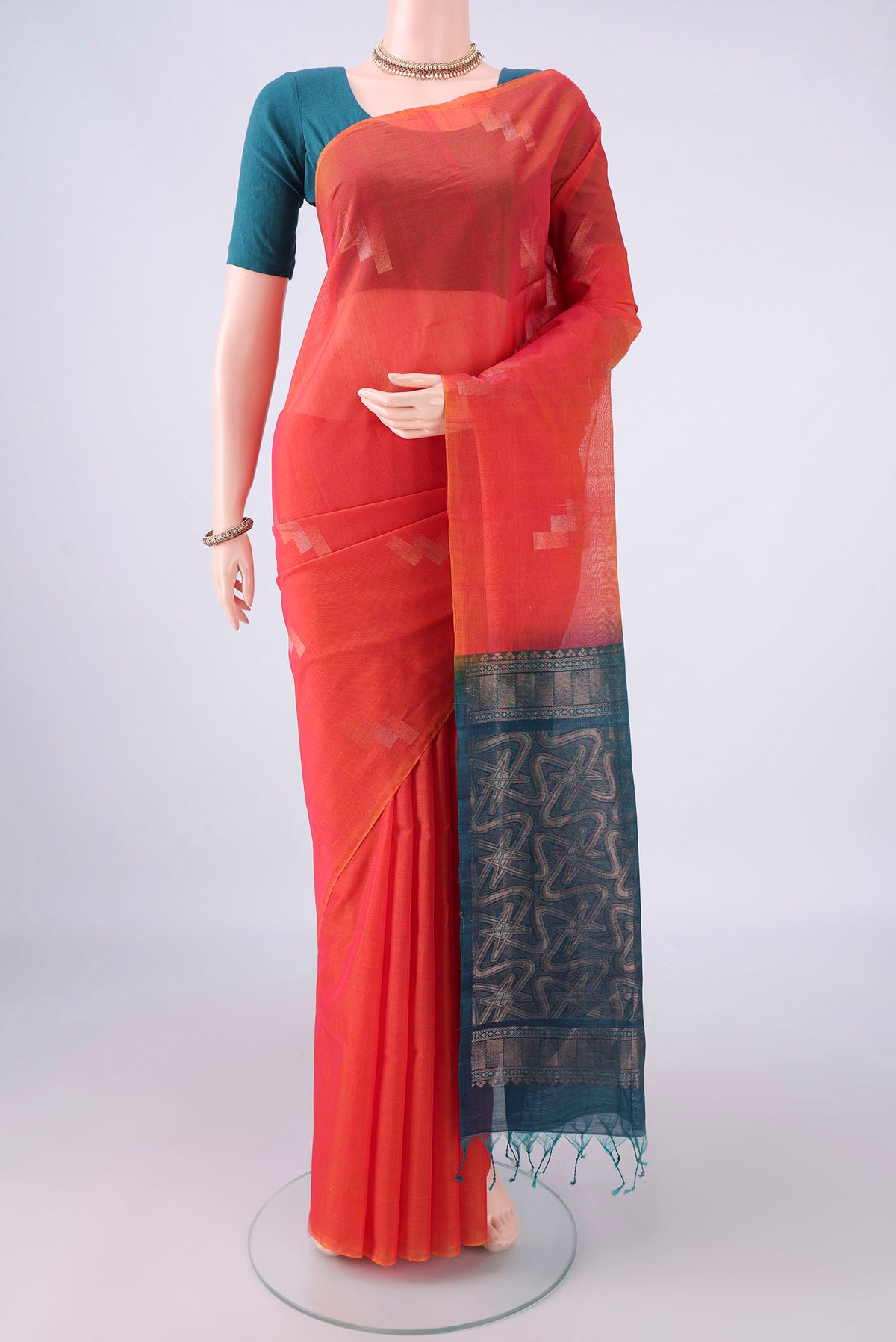 Brick Orange Silk Cotton Saree with Zari Butta on the body and Without Border.  displayed on a mannequin