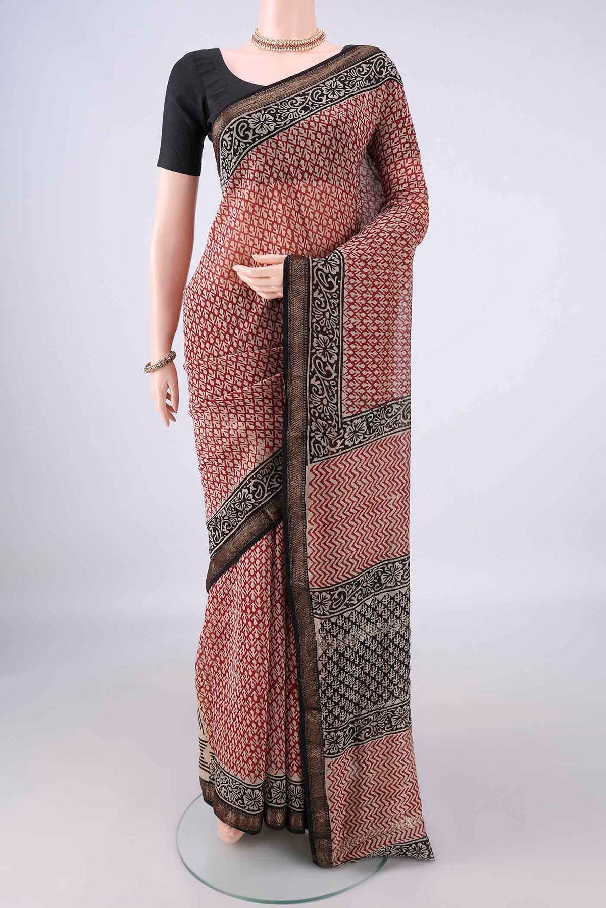 Maroon Maheshwari Cotton Saree with Batik Print on the body and Zari Border.  displayed on a mannequin
