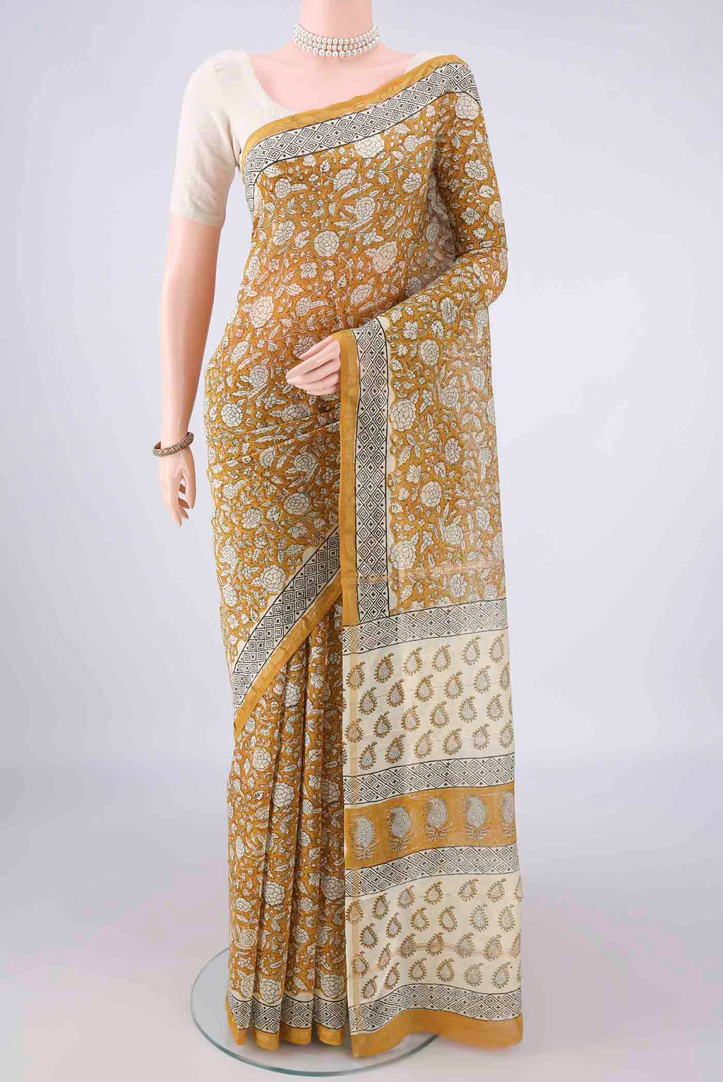 Mustard Chanderi Cotton Saree with Batik Print on the body and Thin Zari Line.  displayed on a mannequin