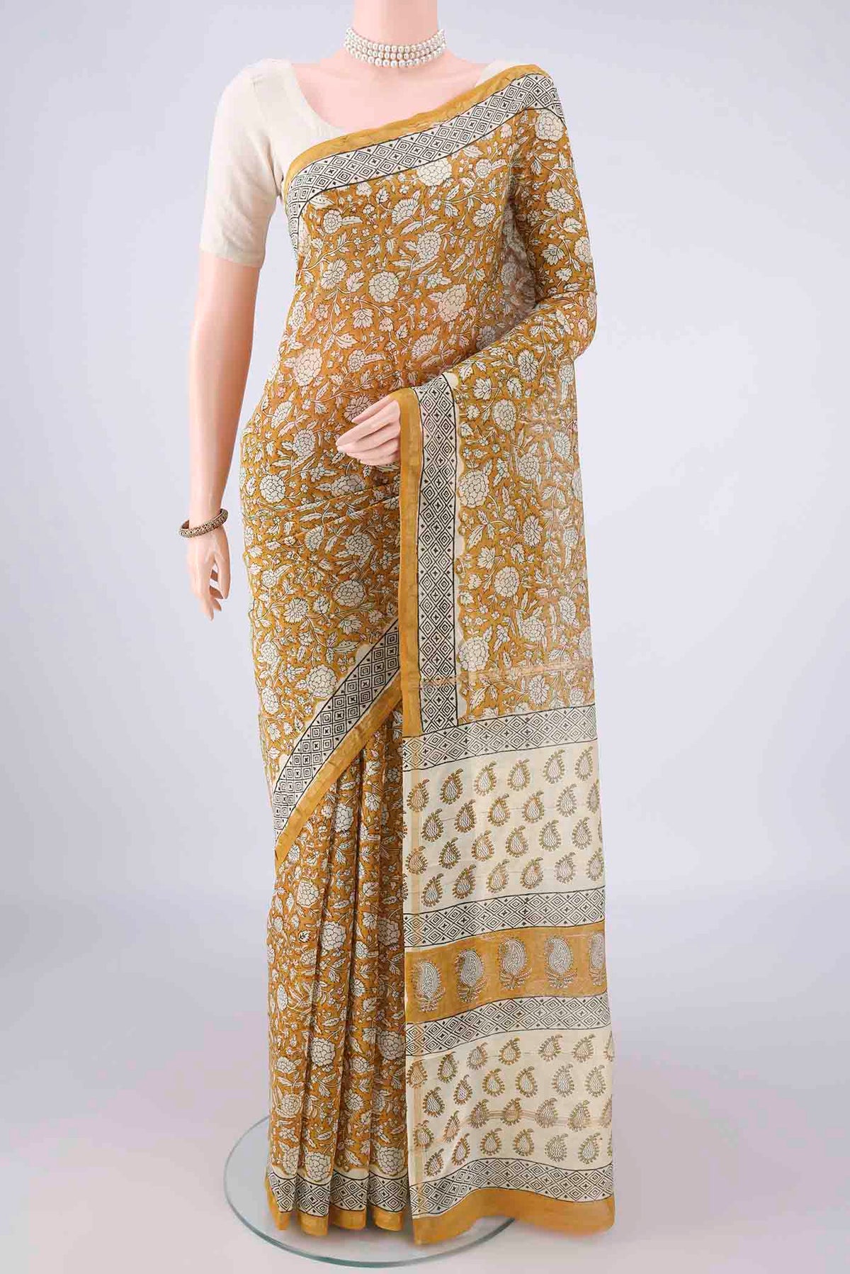 Mustard Chanderi Cotton Saree with Batik Print on the body and Thin Zari Line.  displayed on a mannequin