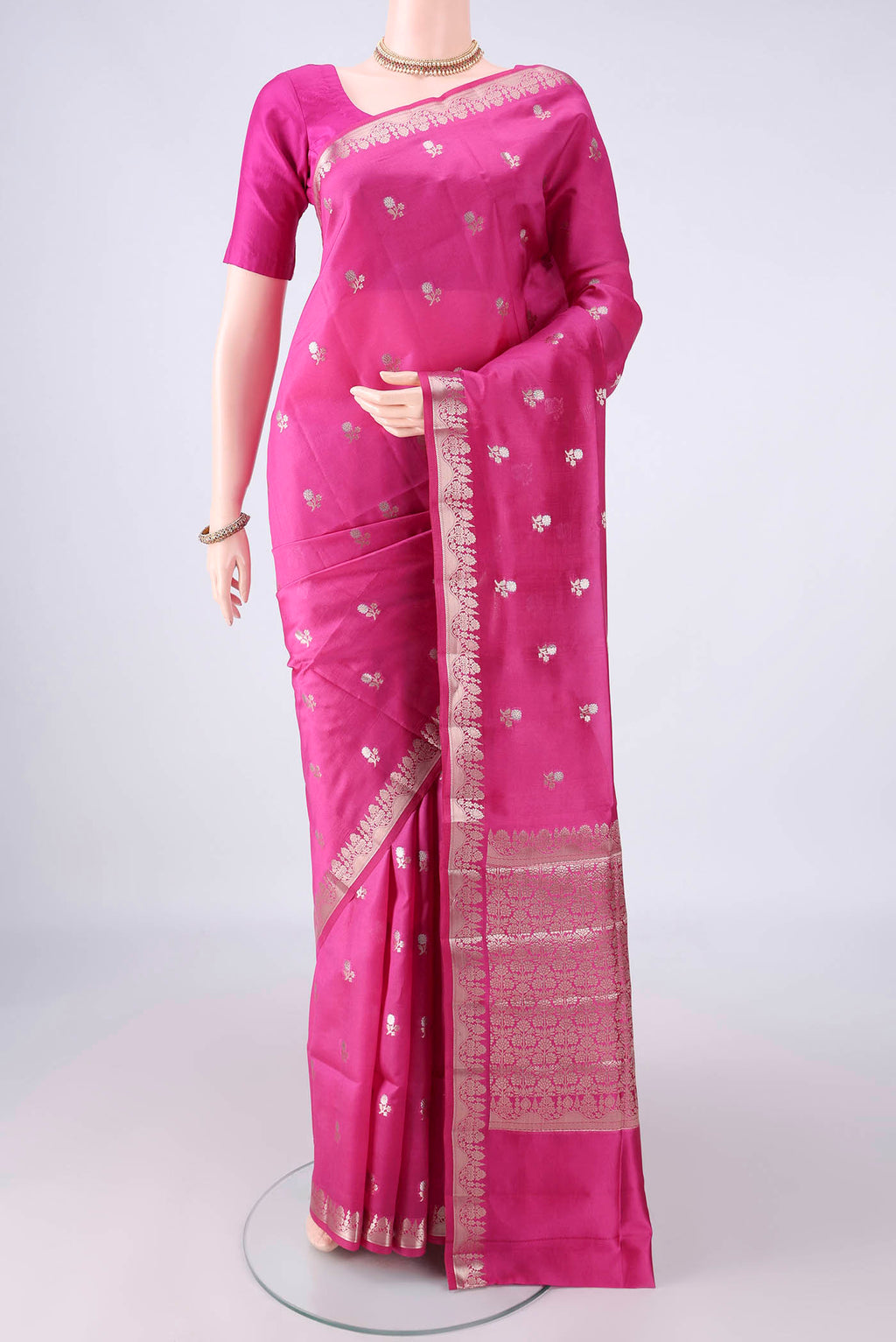 Pure Silk Rani Pink Banarasi Raw Saree with Zari Butta on the body and Zari Border.  displayed on a mannequin