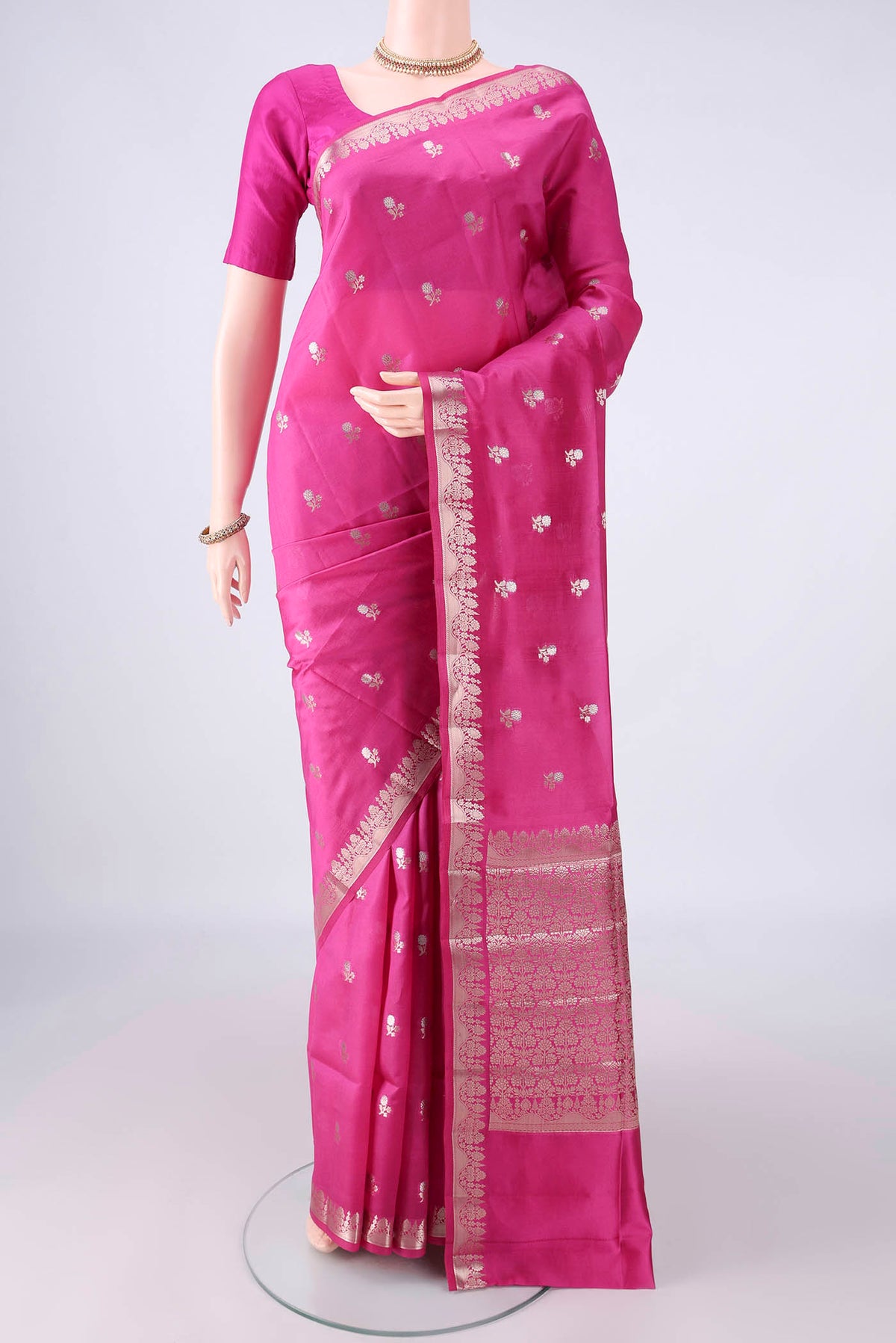 Pure Silk Rani Pink Banarasi Raw Saree with Zari Butta on the body and Zari Border.  displayed on a mannequin