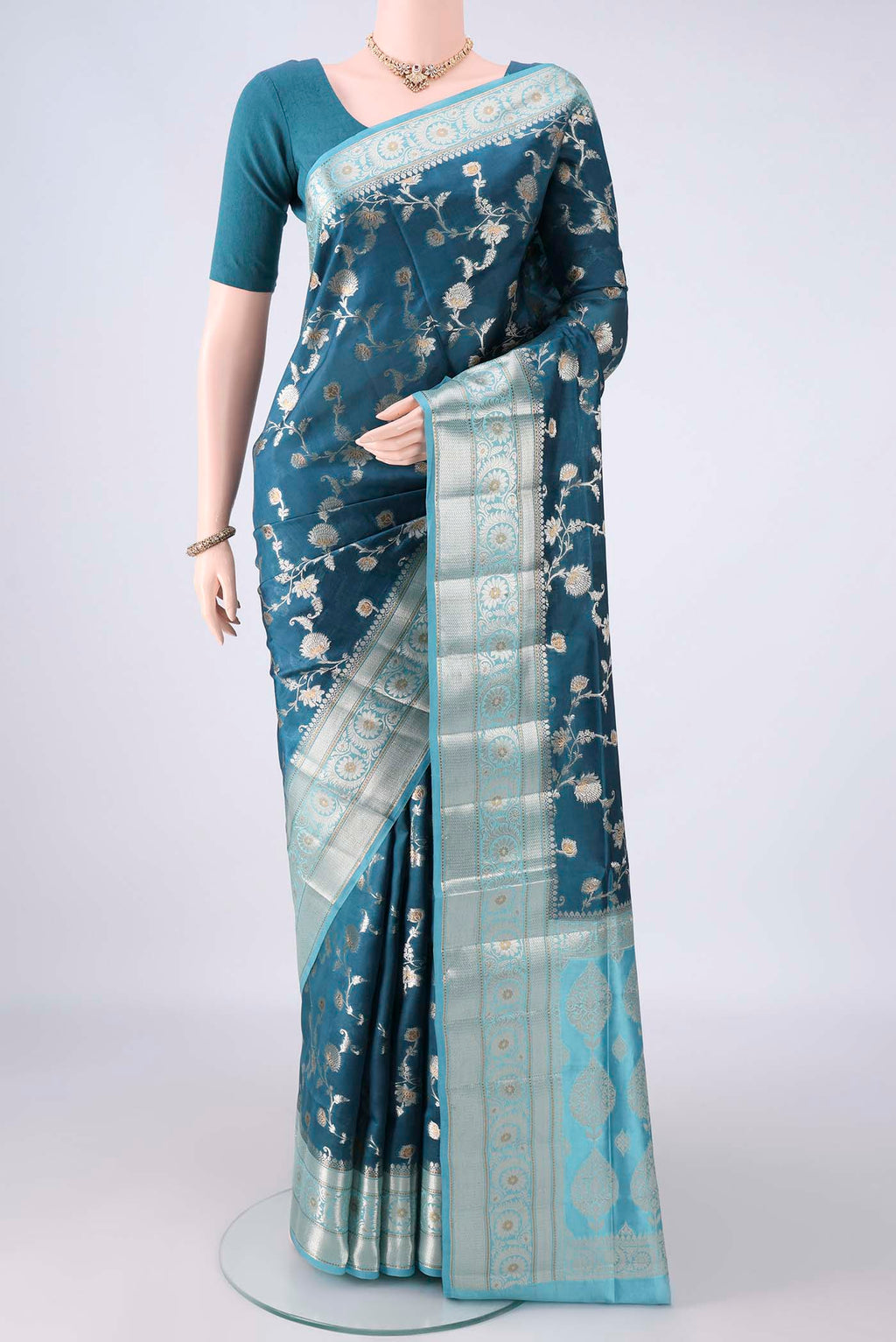 Pure Silk Teal Banarasi Raw Saree with Zari Brocade on the body and Zari Border.  displayed on a mannequin