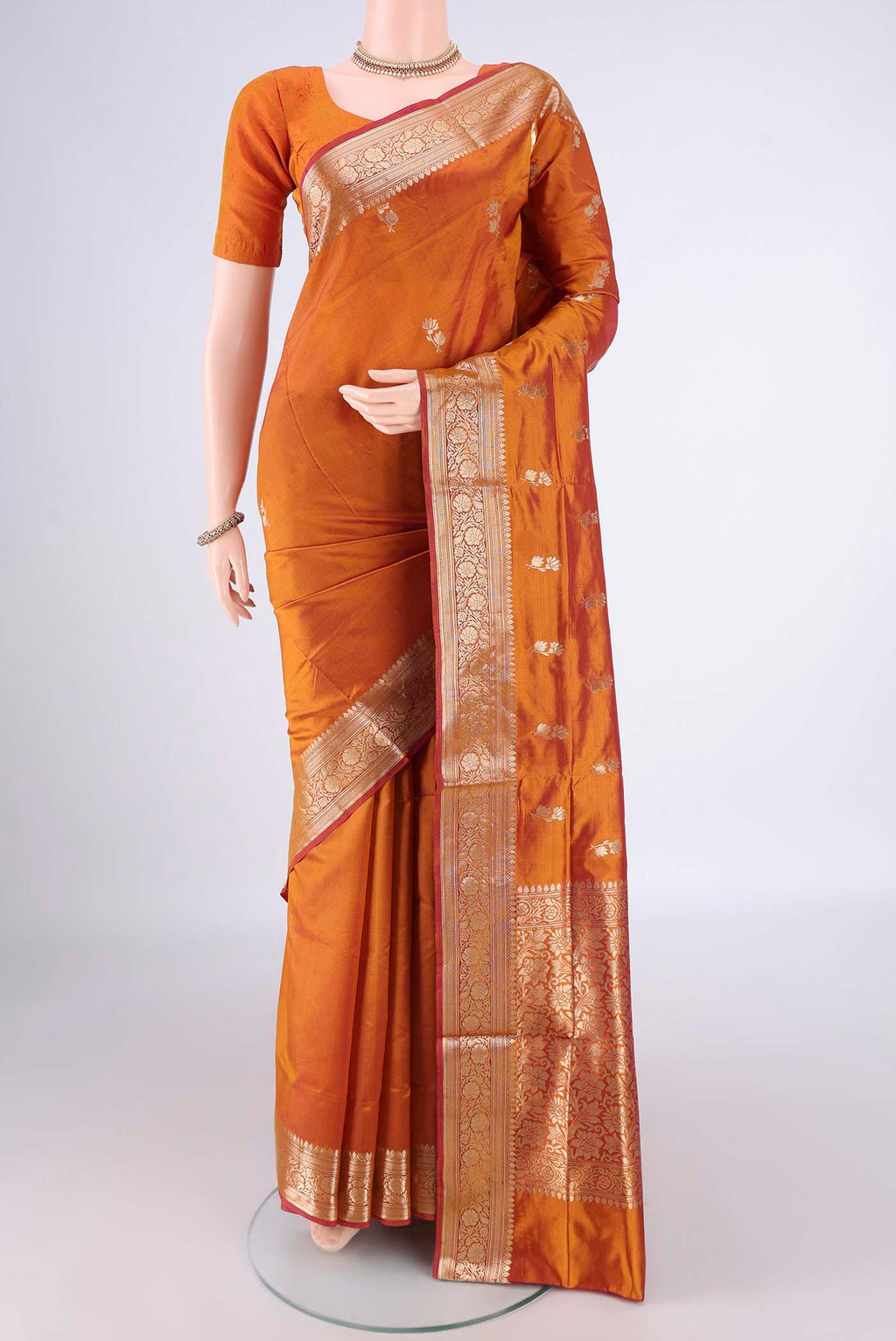 Pure Silk Brick Orange Banarasi Katan Saree with Zari Butta on the body and Zari Border.  displayed on a mannequin