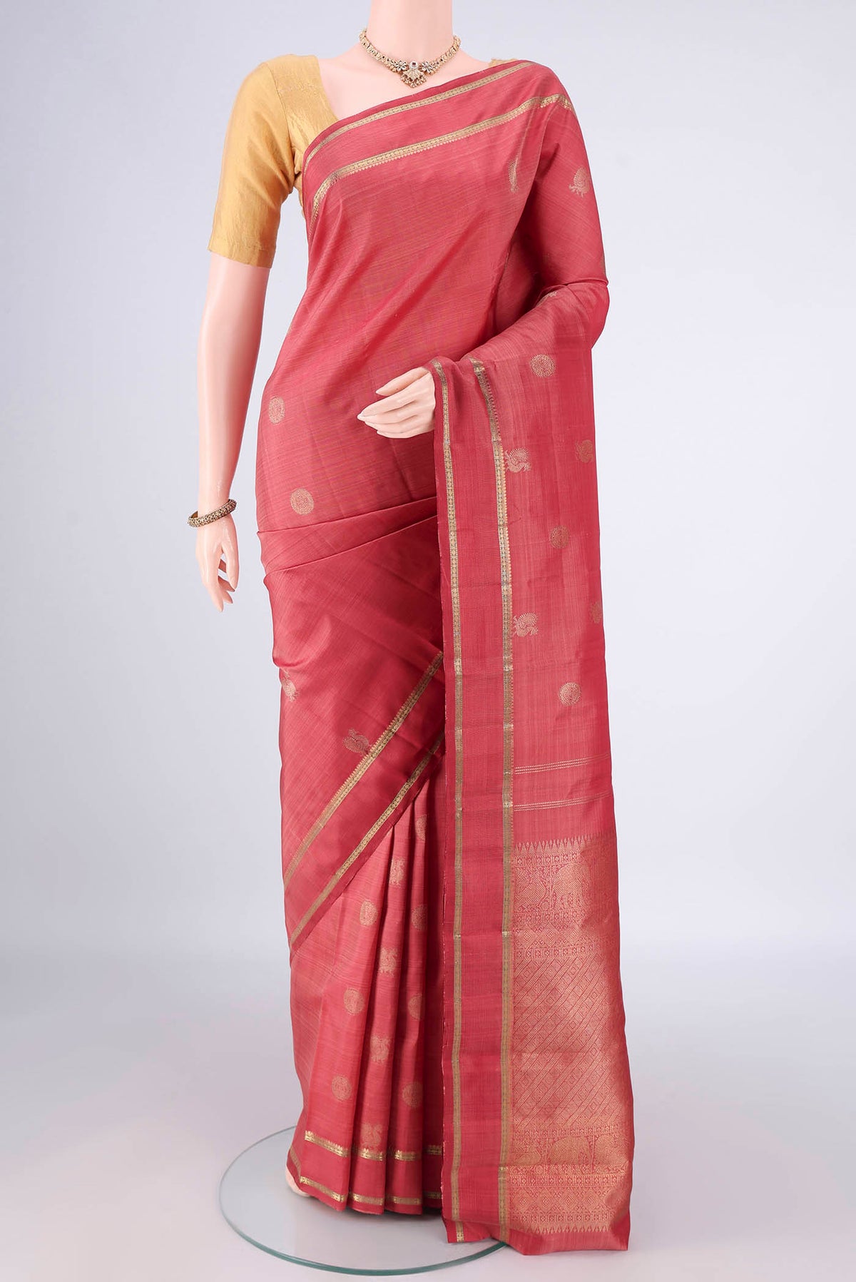 Pure Silk Pure Zari Coral Kanchipuram Saree with Zari Butta on the body and Zari Border.  displayed on a mannequin