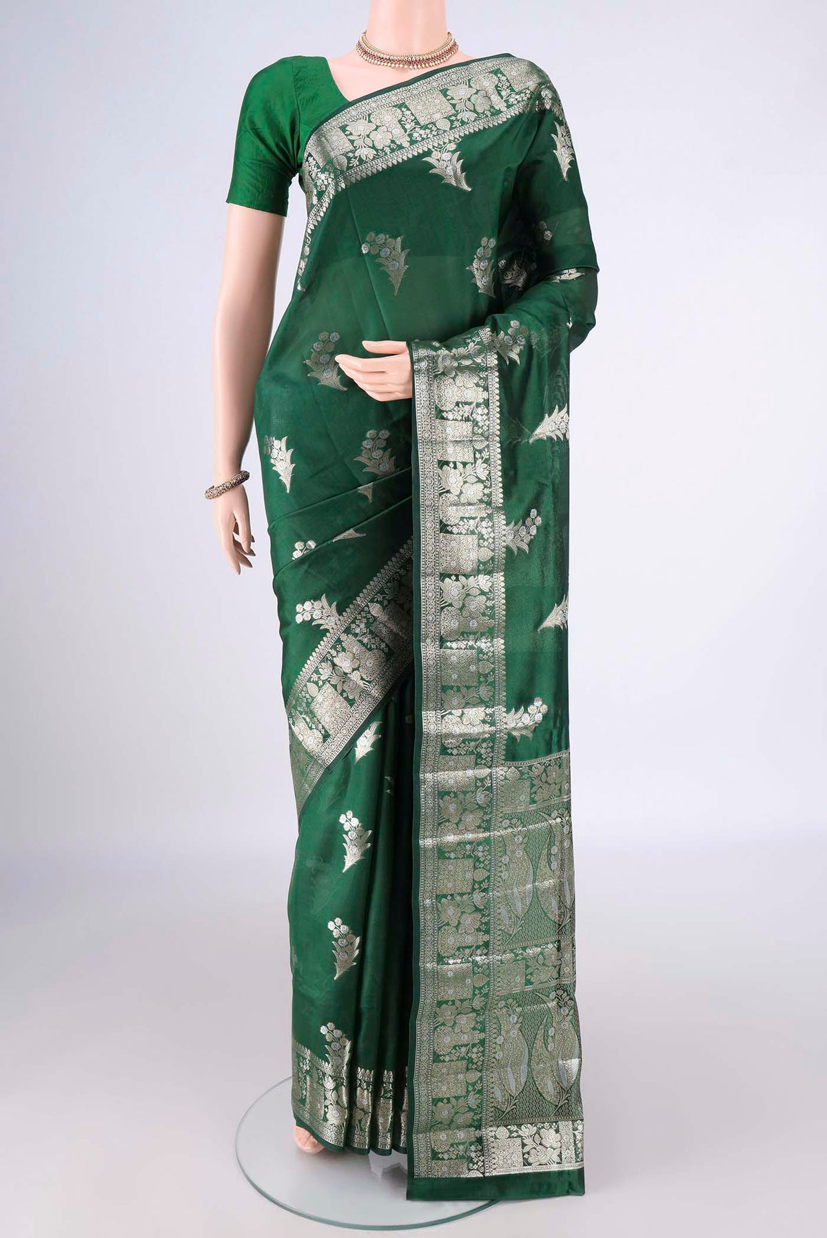 Pure Silk Bottle Green Banarasi Raw Saree with Zari Butta on the body and Zari Border.  displayed on a mannequin