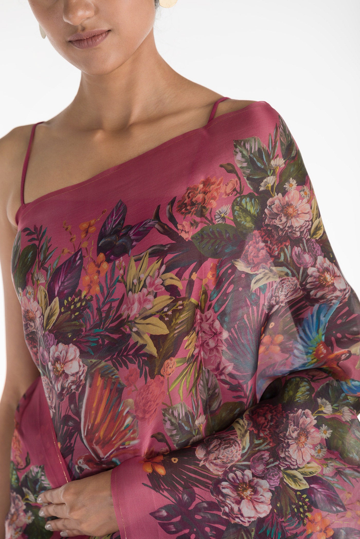 Close up of Our 'Hyacinth Macaws' Satin Organza Saree is crafted in a pink tone that features hand-illustrated tropical prints of macaws flying around tropical florals. The saree is completed with the sheen of detailed thin Zari lines. displaying folds