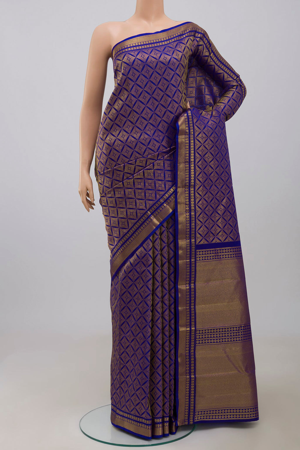 Handwoven in pure mulberry silk with half-fine gold and silver zari, this blue Kanjeevaram saree celebrates the harmony of line and light. A refined checkered pattern, formed by intersecting gold zari lines, unfolds across the body and continues into the radiant gold pallu. Framed by two broad gold bands separated by a slender gold stripe, the border lends the weave timeless balance and elegance. displayed on a mannequin