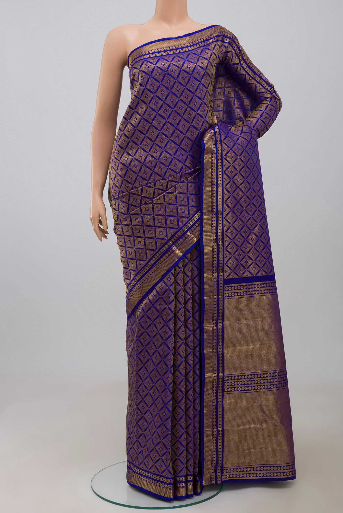 Handwoven in pure mulberry silk with half-fine gold and silver zari, this blue Kanjeevaram saree celebrates the harmony of line and light. A refined checkered pattern, formed by intersecting gold zari lines, unfolds across the body and continues into the radiant gold pallu. Framed by two broad gold bands separated by a slender gold stripe, the border lends the weave timeless balance and elegance. displayed on a mannequin