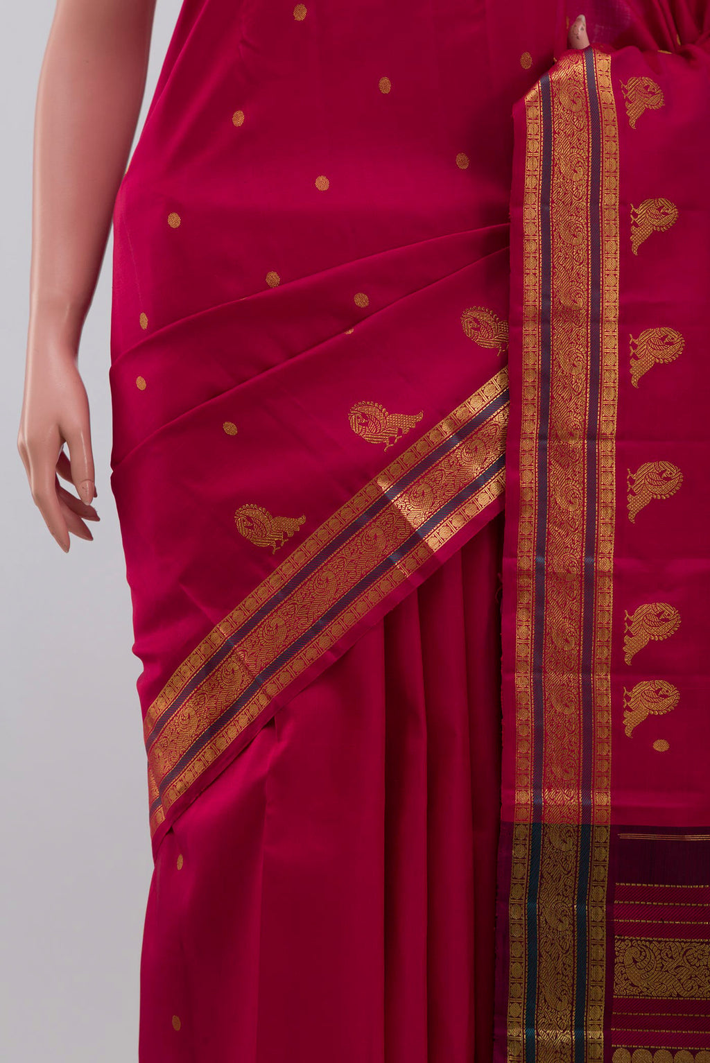 Close up of Aaradhya unfolds in a vibrant scarlet red, adorned with delicate rudraksh butas that bring depth and rhythm to the weave. The 3-inch borders feature mayil zari pet and rudraksh pet framed by contrasting silk bands. Along the lower border, graceful mayils with unfurled wings create a striking visual detail. The pallu is highlighted by a distinctive grid pattern accented with vibrant green bands displaying folds
