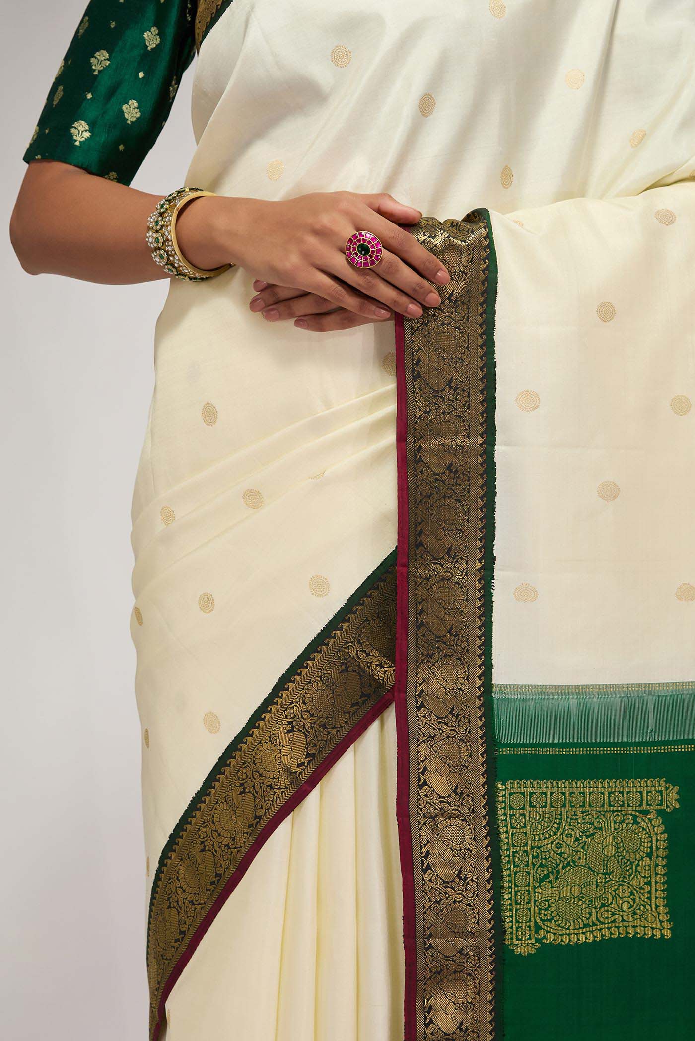 Close up of Off White Kanchipuram Silk Saree with Zari Butta on the body and Zari Border displaying folds