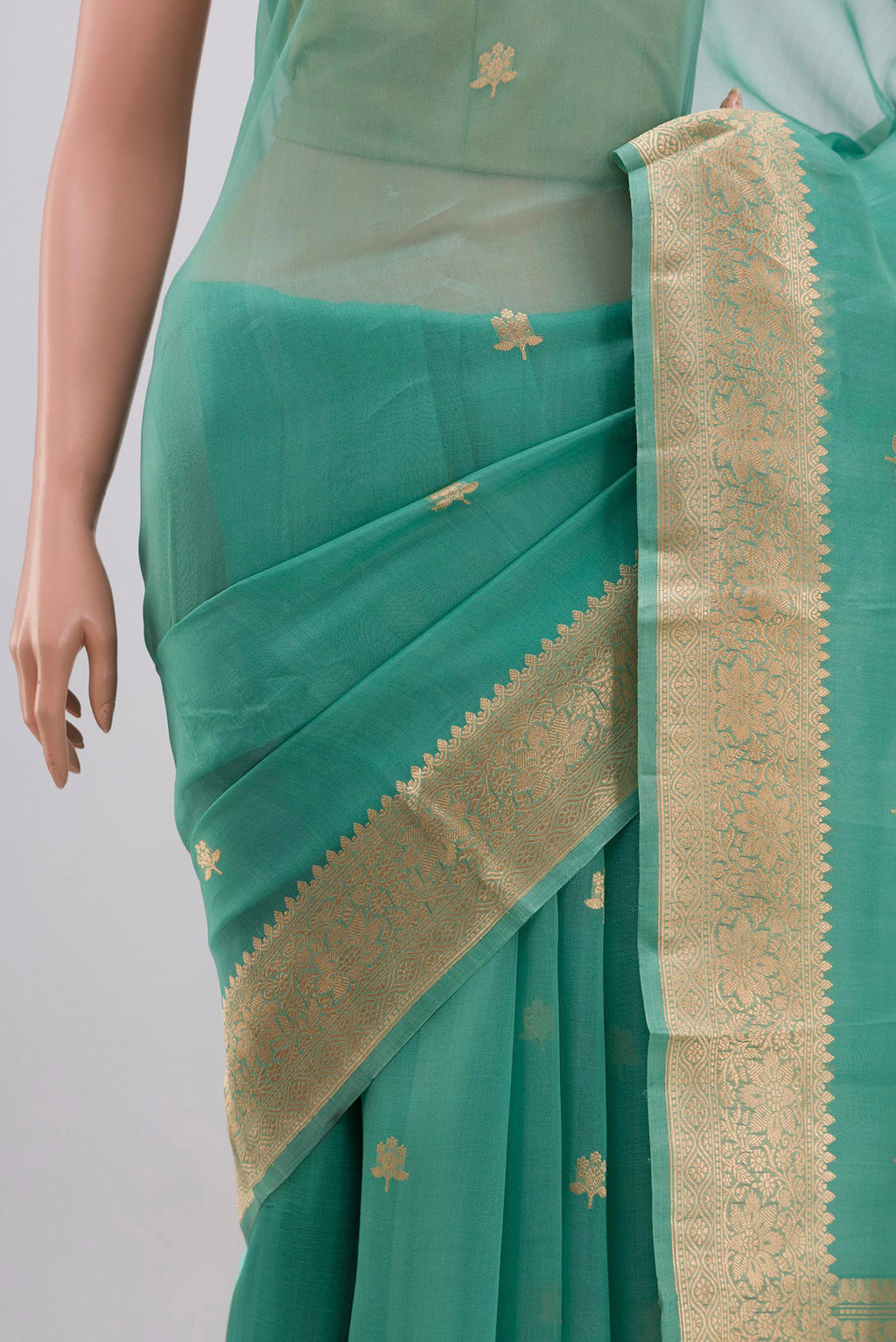 Close up of Green Organza Silk Saree with Zari Butta on the body and Zari Border displaying folds
