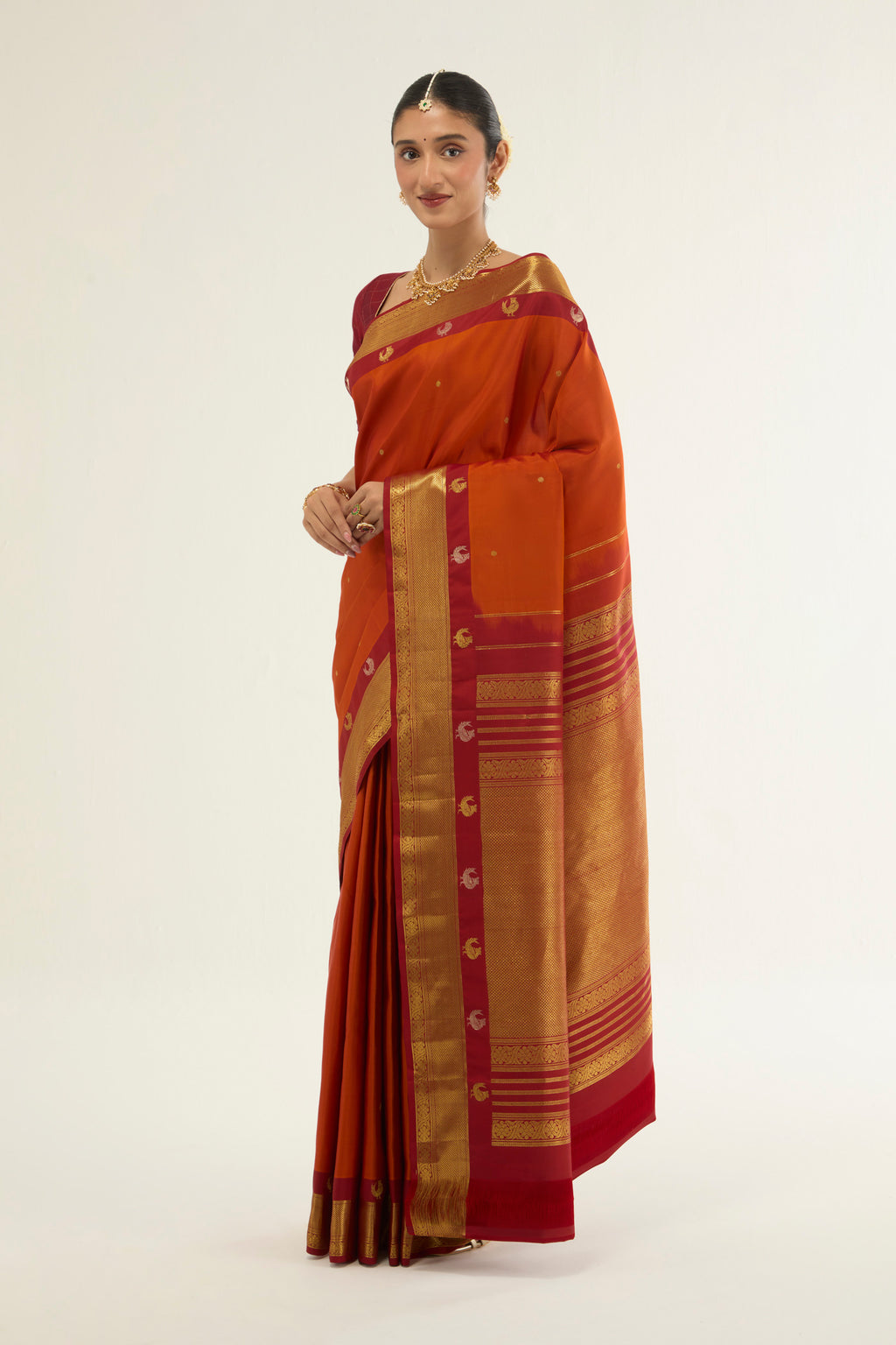 Close up of Orange Kanchipuram Silk Saree with Zari Butta on the body and Zari Border displaying folds