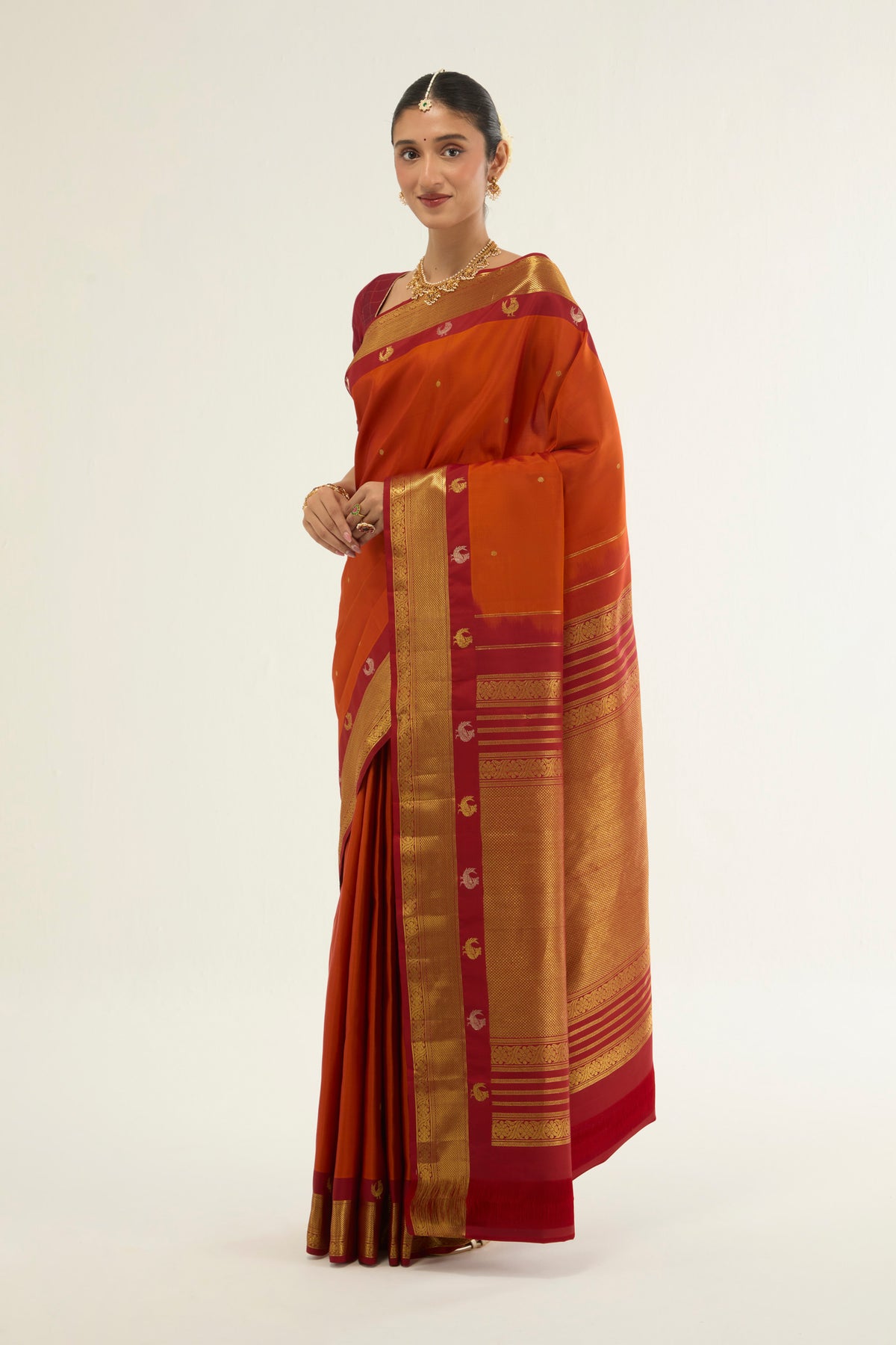 Close up of Orange Kanchipuram Silk Saree with Zari Butta on the body and Zari Border displaying folds