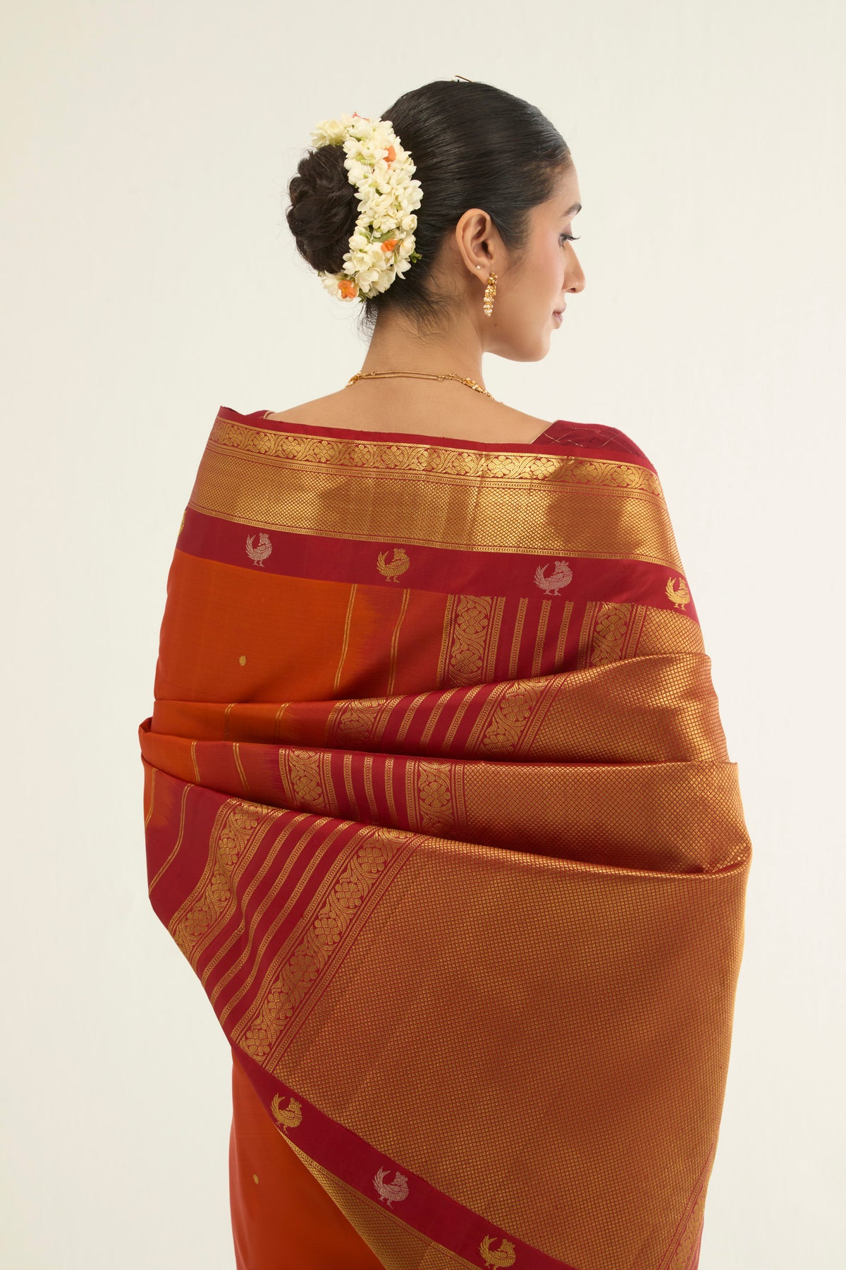 Close up image of the pallu of Orange Kanchipuram Silk Saree with Zari Butta on the body and Zari Border